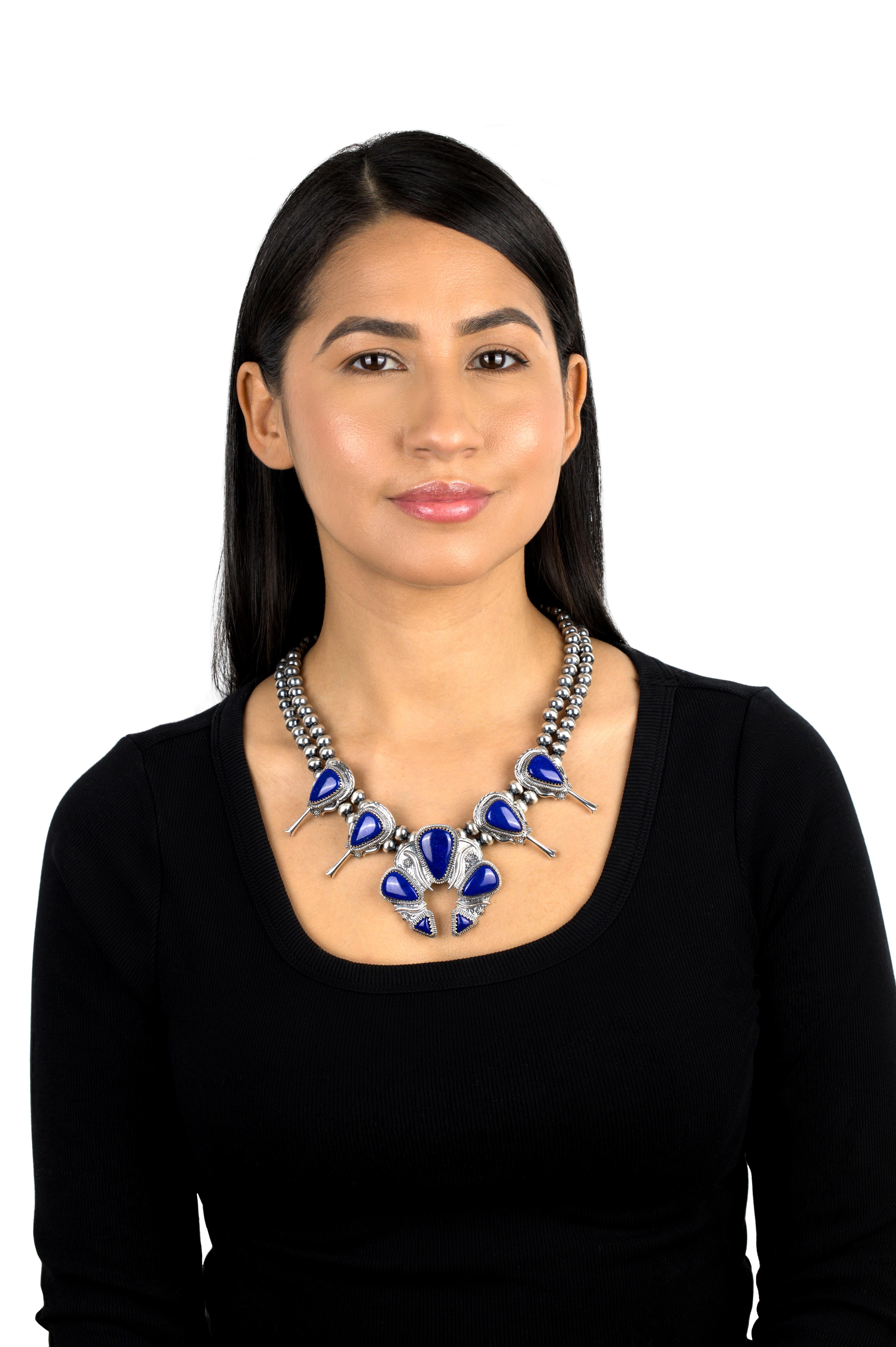 Presenta perle native in argento satinato da 8 mm, 4 stazioni Squash Blossom con cabochon di Lapis a forma di triangolo, 2 su ciascun lato di una grande Naja con 5 cabochon triangolari graduati.
- Misura 21