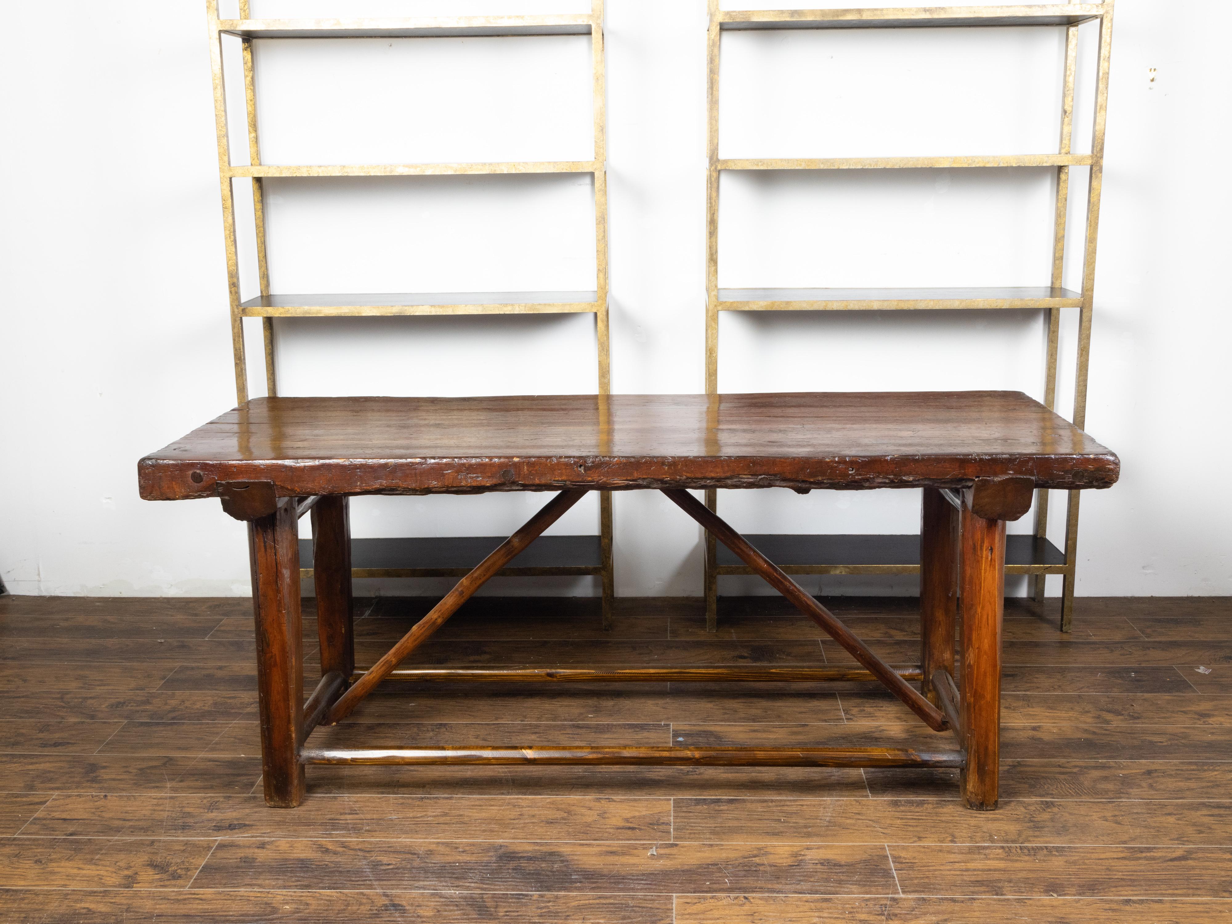 An American rustic pine log table from the early 20th century, with straight legs and side stretchers. Made in the USA during the early years of the 20th century, this pine log table features a rectangular planked top sitting above four straight