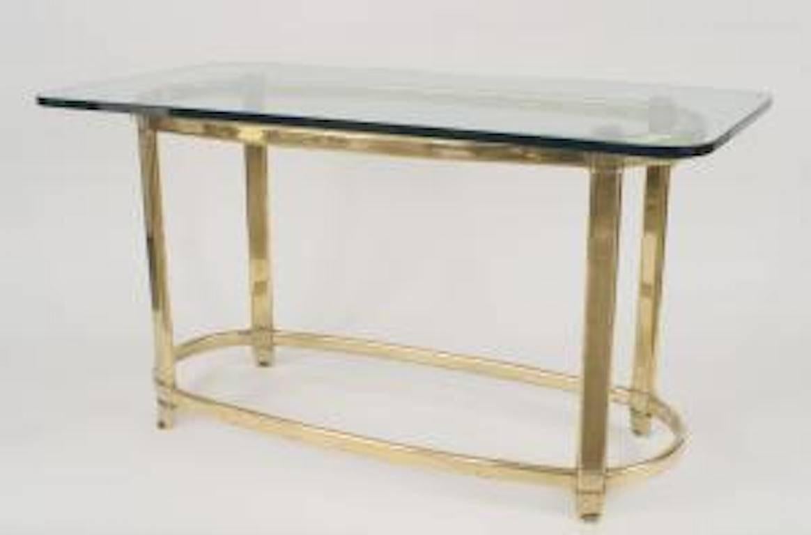 American 1940s style center table with an oval brass base with an oval stretcher supporting a rectangular glass top.
