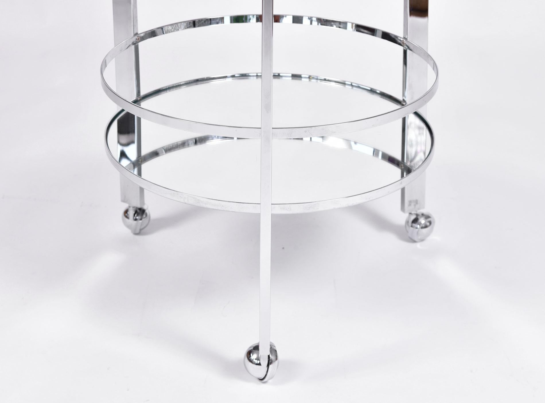 Two-tiered chrome circular drinks trolley/serving cart with chic modern frame. Mirrored glass bottom shelf adds beautiful reflection. Chrome covered caster wheels for smooth movement.
  