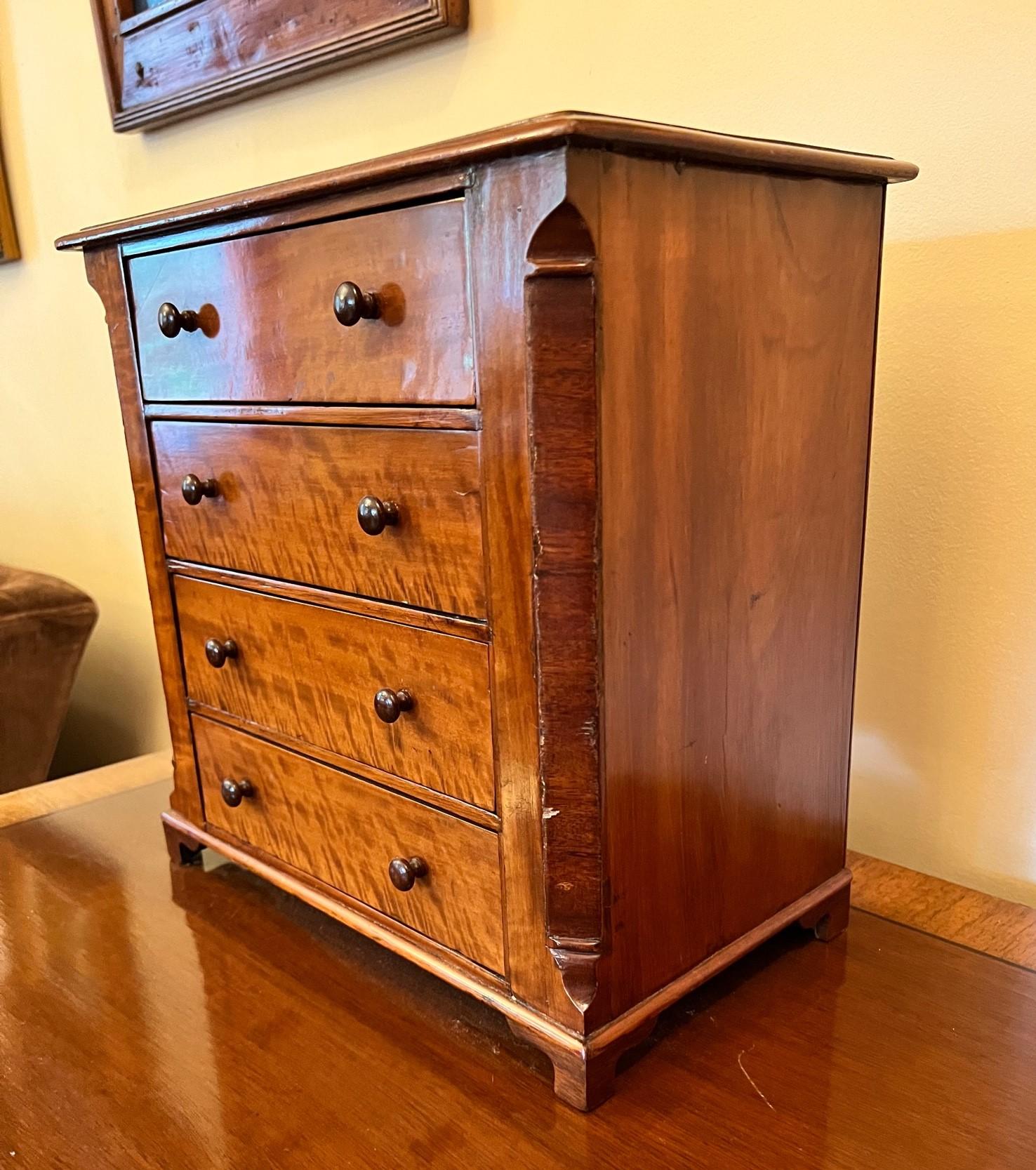 19th c., American, four drawer miniature chest with Sheraton style pulls, on scalloped blocked feet. This attractive salesman sample is characterful with a lovely deep aged cherry color. This is one of the most attractive miniature chests of drawers