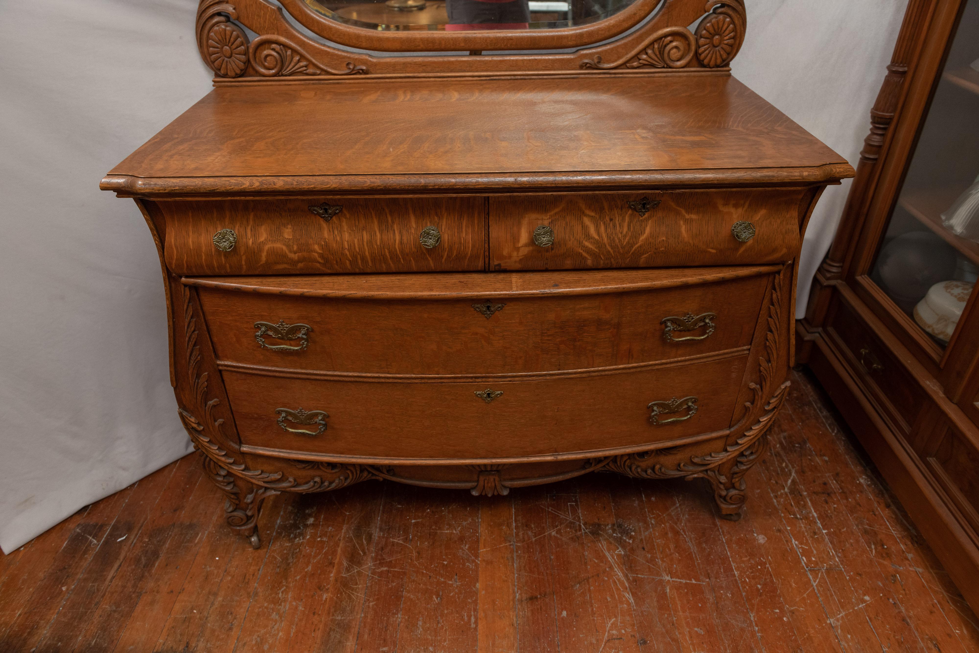 This incredible oak dresser, or bureau if you prefer, is top of the line oak, circa 1900. The box front drawers, bombe (curved) sides, big beveled shield shape mirror and original brass pulls are what makes this an exceptional example of turn of the