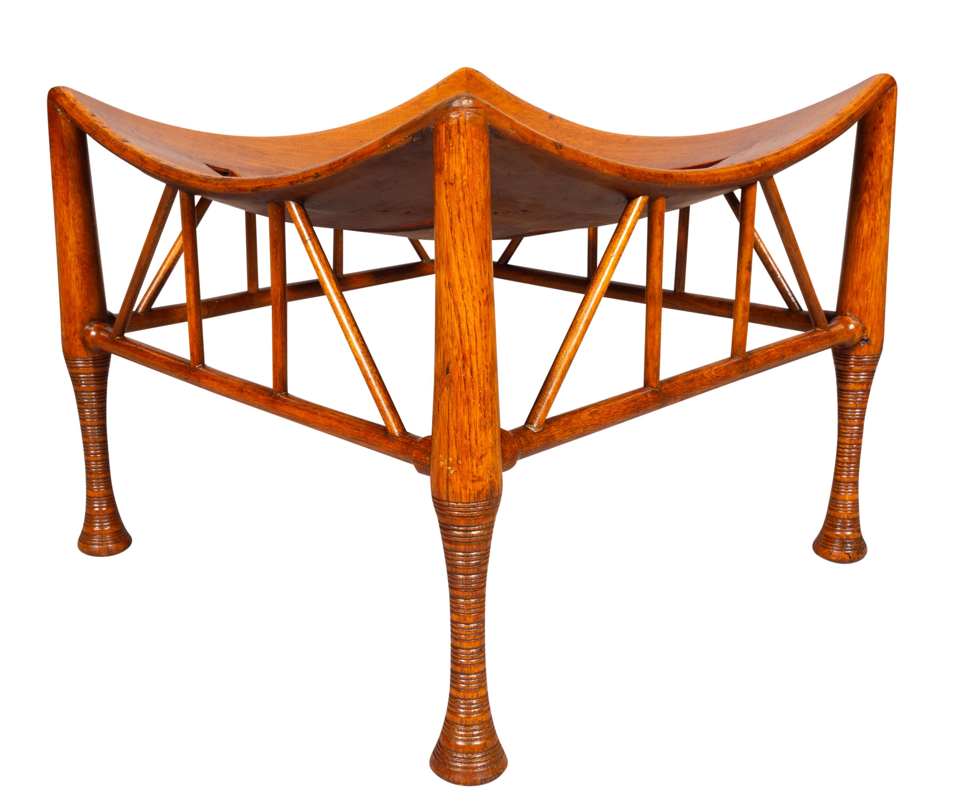 Square in the Egyptian revival style. Curved slat seat with turned legs and stretchers.