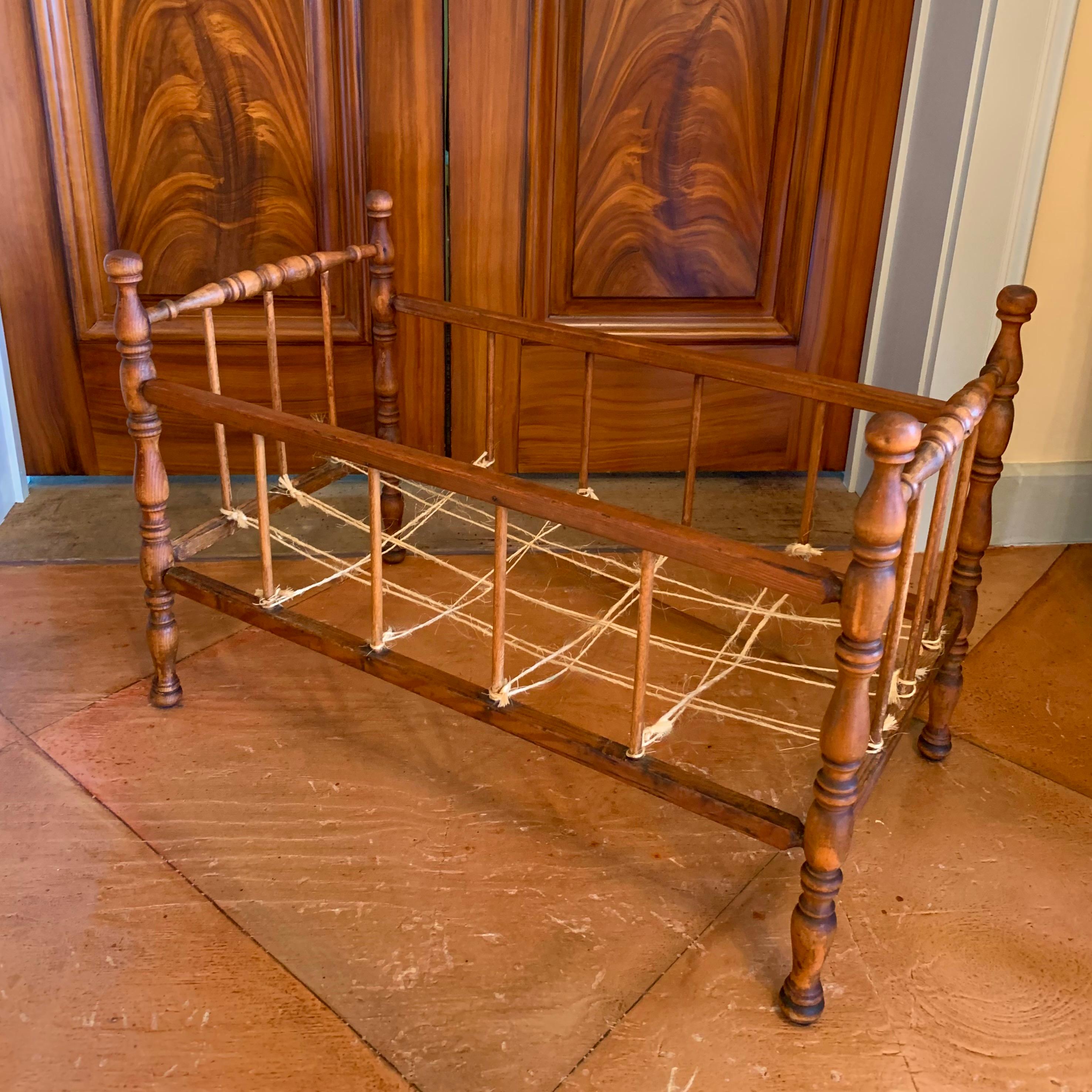 Ein aus Ahorn und Kiefer gedrechseltes Puppenbett aus der Mitte des 19. Jahrhunderts mit schönen Proportionen, mit detaillierten Drechselarbeiten an den vier Bettpfosten. Der Boden ist mit natürlichem Bindfaden 