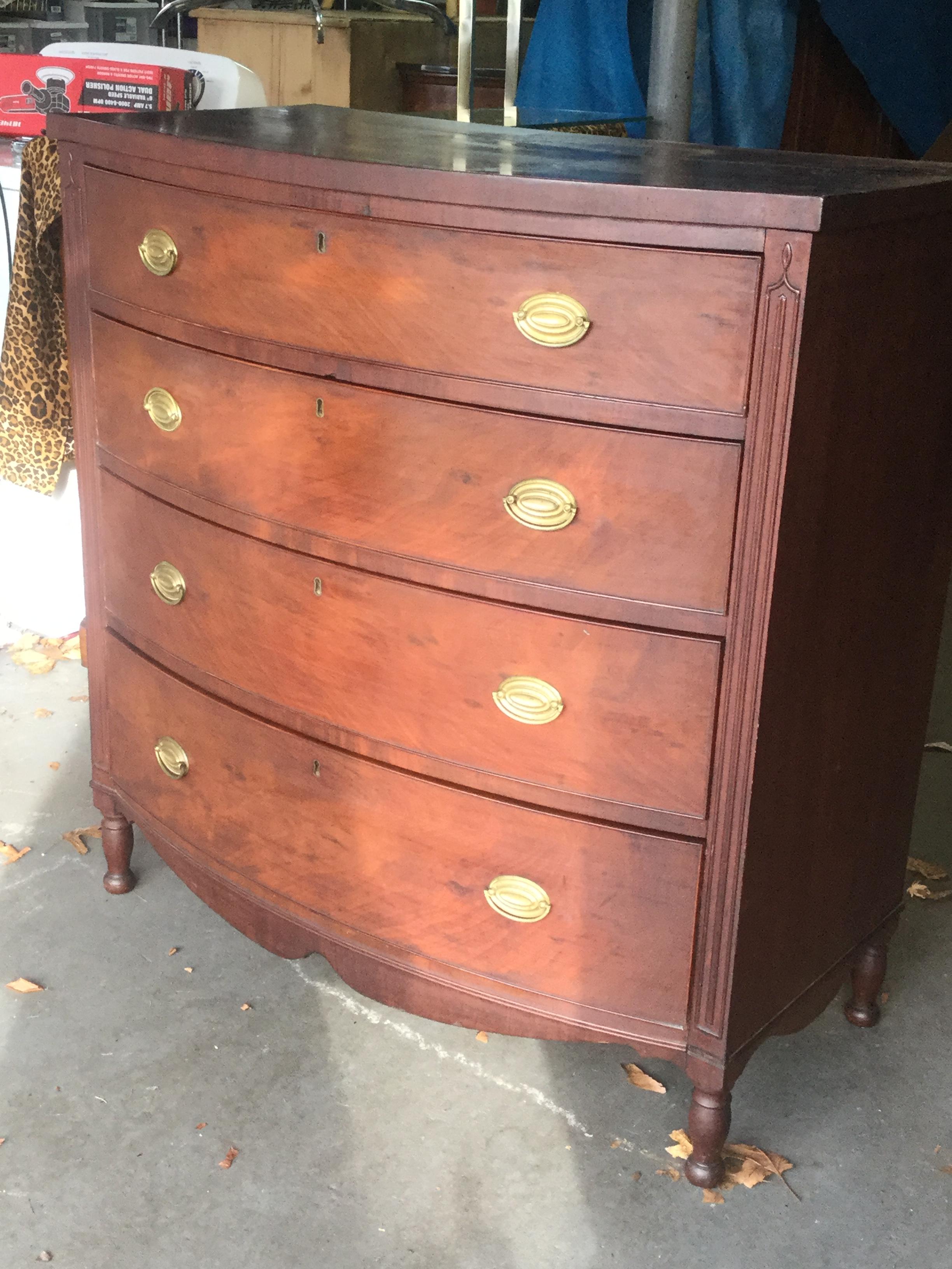 Handsome and elegant describe this traditional American mahogany chest of drawers. With a slightly bombe front, this chest features 4 large and deep drawers for ample storage. Drawer fronts are made of flame mahogany, and the brass pulls are