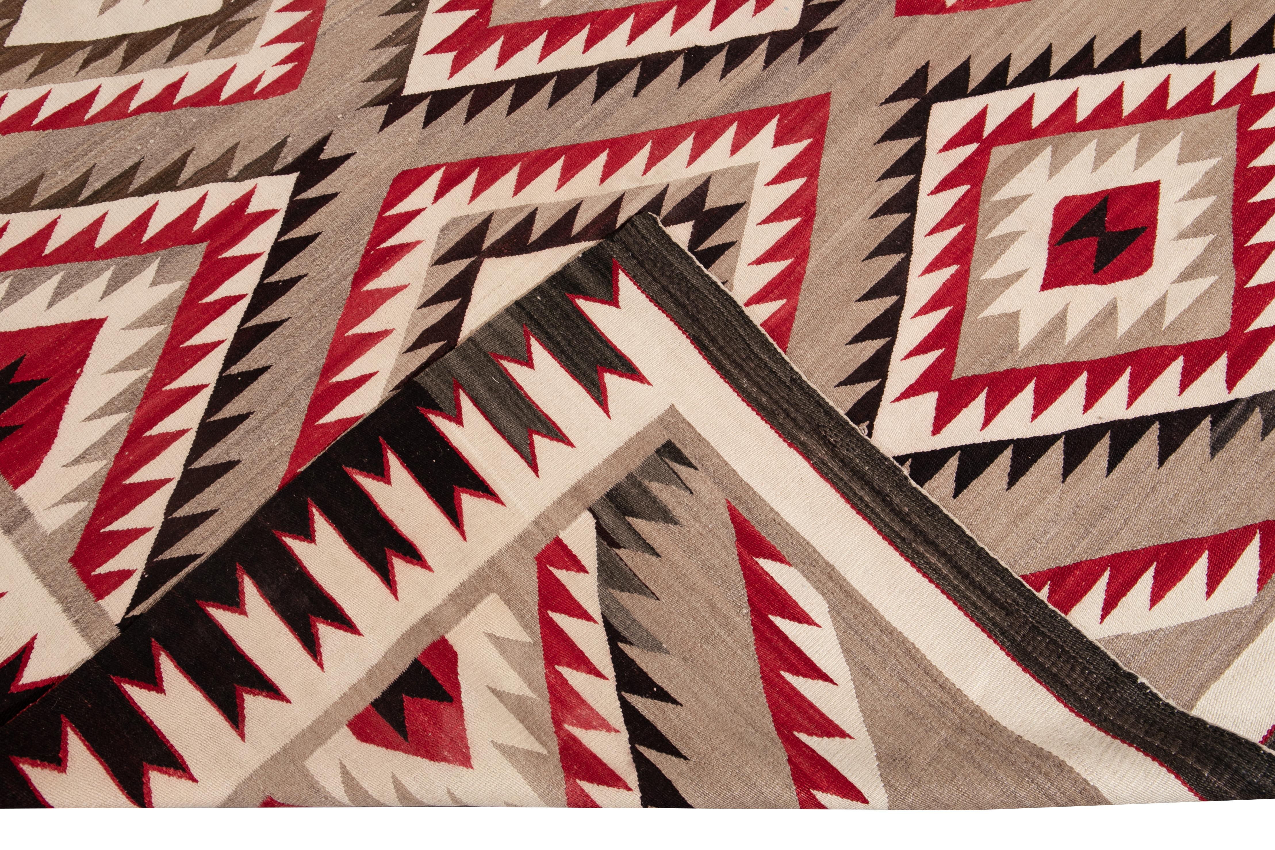 American antique Navajo geometric Folk Navajo flat-weave wool rug tan field. This Navajo rug has ivory, brown, and red accents in a gorgeous all-over geometric design.

This rug measures: 7'11