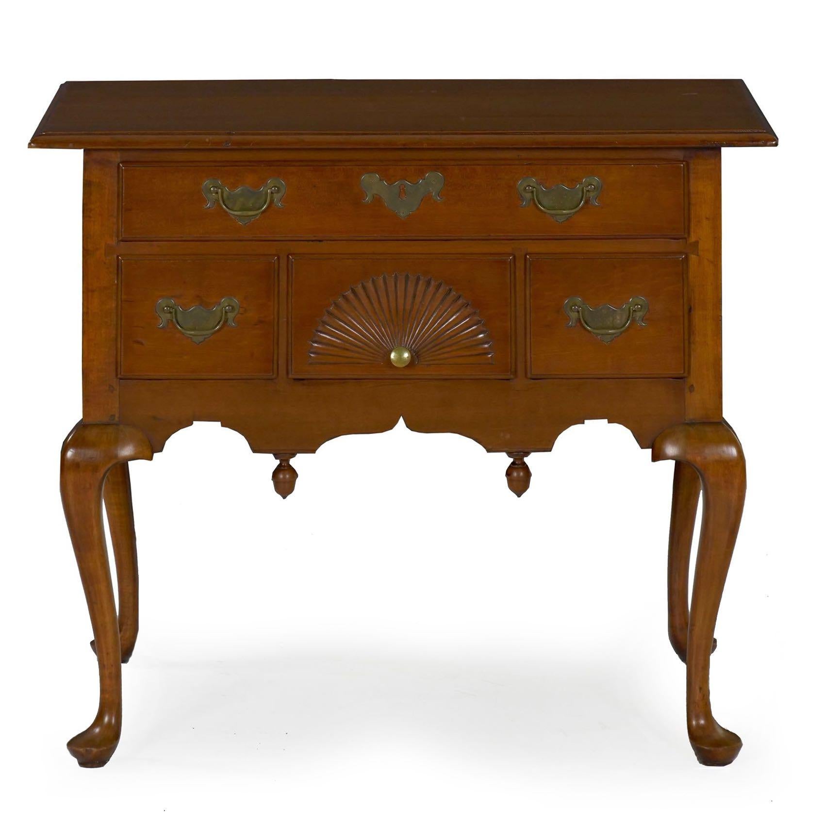 The generously projected maple top is affixed with a series of square wooden pegs, the two-board top edged by integral thumb-molding over a conforming case arranged with a single horizontal drawer over a fan-carved central drawer flanked by a pair