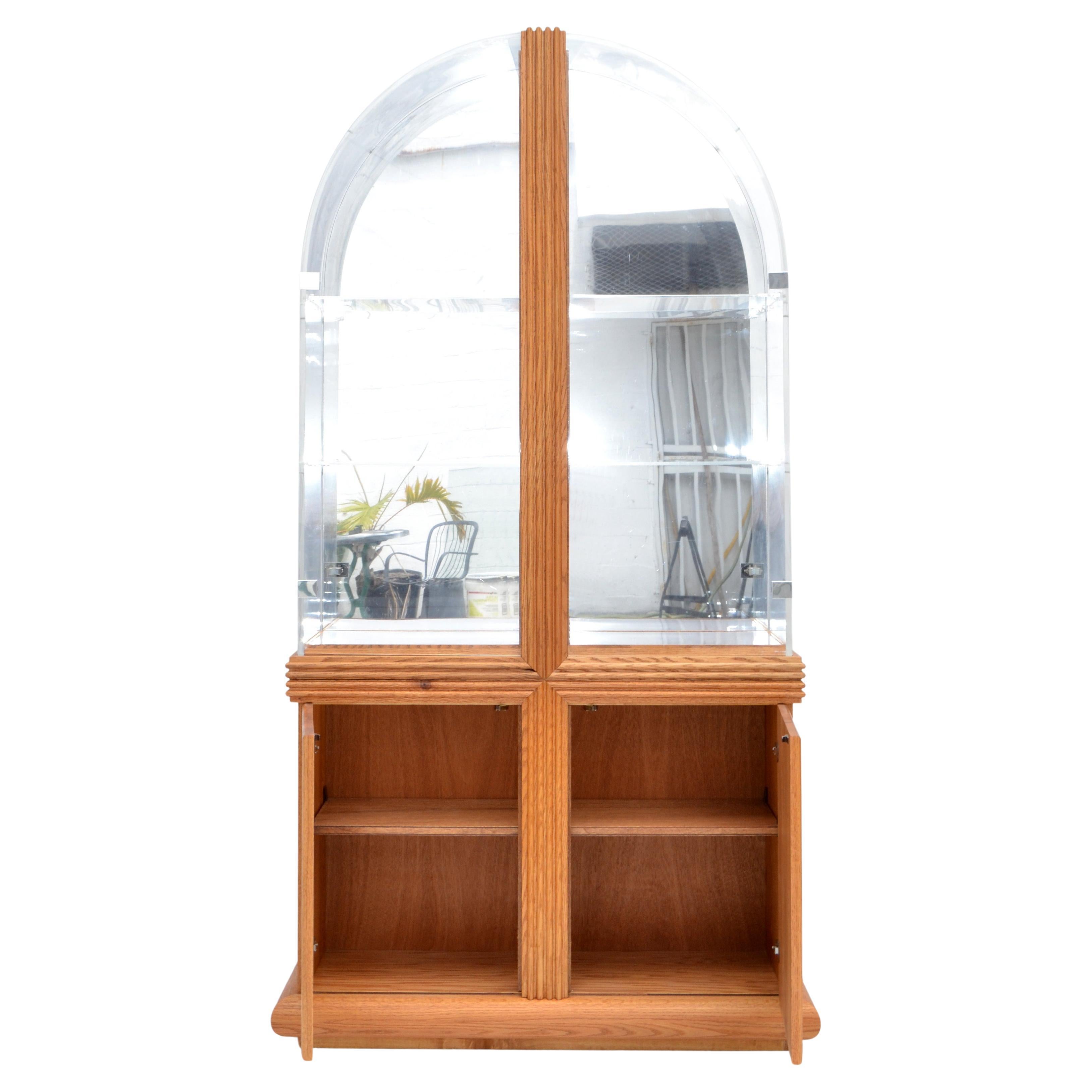 Mid-Century Modern two piece arched Lucite top Vitrine, showcase, bookshelf made in America 1980 with a blonde Oak Wood Cabinet Base.
Features a mirrored Back and 2 tier clear Lucite shelves, the bottom shelf is white Acrylic and will illuminate