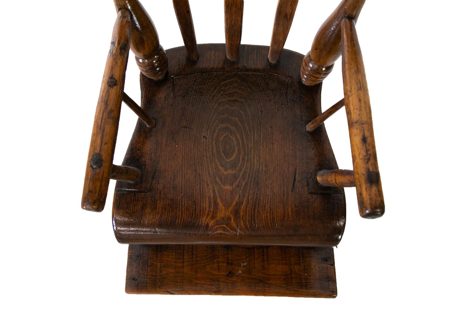 American arrow back high chair has a pine saddle seat and oak arrow splats. The legs and top are tulip poplar. The seat has incised decoration which is partially worn. The front legs have four turned bands at the top of the legs and two below the