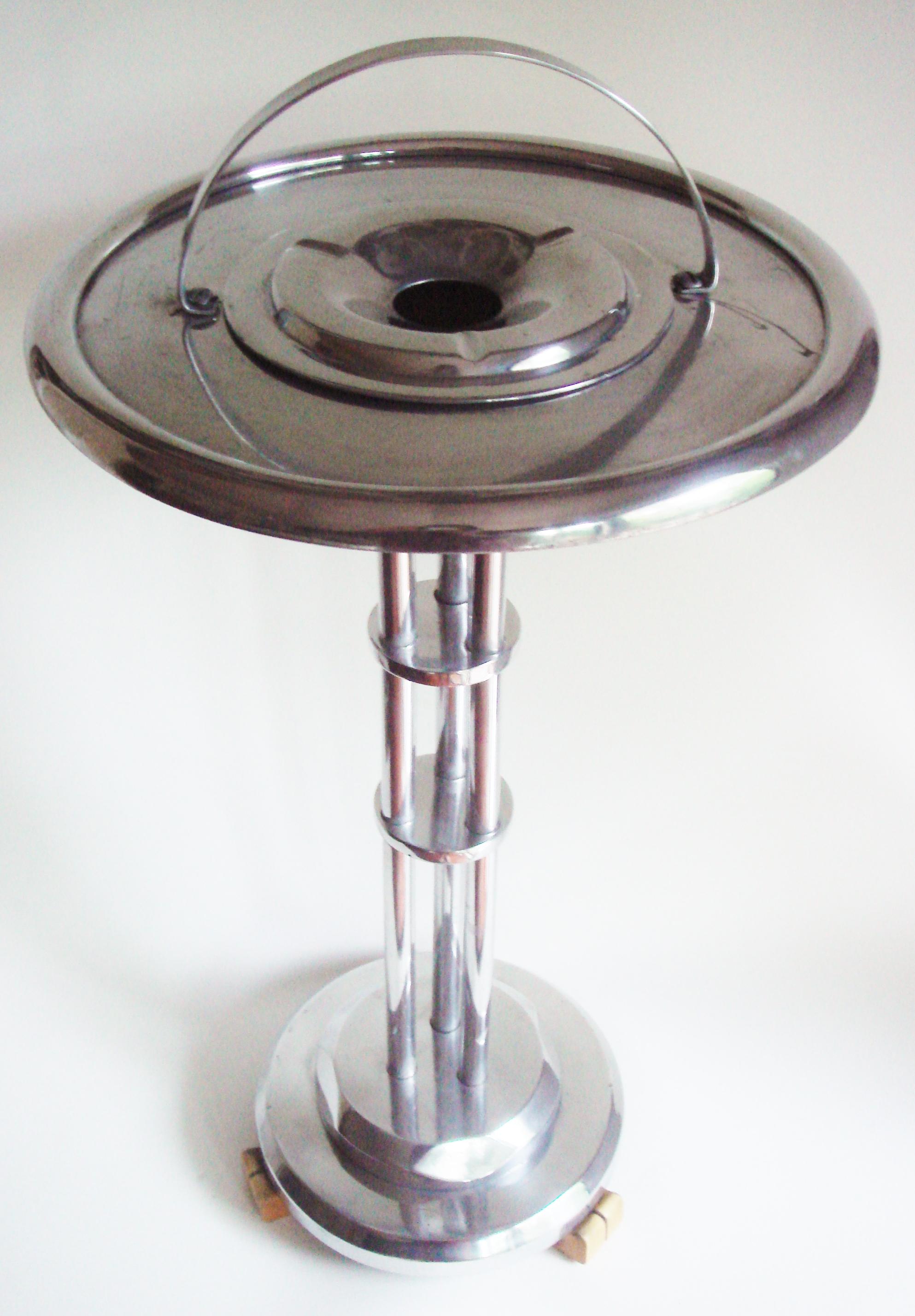 This stunning rare American Art Deco/Machine Age polished Aluminum floor standing ashtray/smoker's table stands on three butterscotch Bakelite feet. It looks as though it should be in Buck Roger's man cave. (Please see photo as it does have a