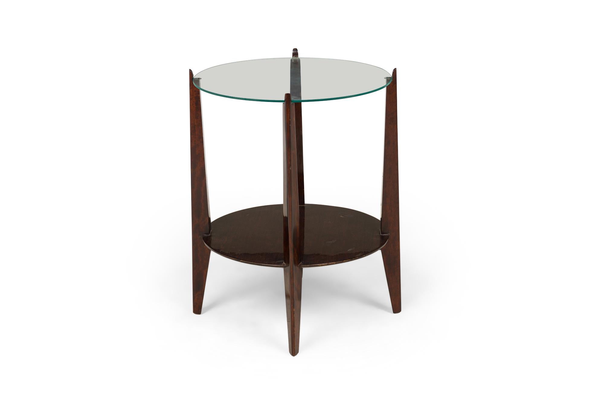 Mesa auxiliar / auxiliar americana Art Decó con tablero circular grueso de cristal transparente apoyado en una base de caoba lacada de cuatro postes con un estante inferior circular en forma de camilla.

Estado: Bueno; Desgaste acorde con la edad y