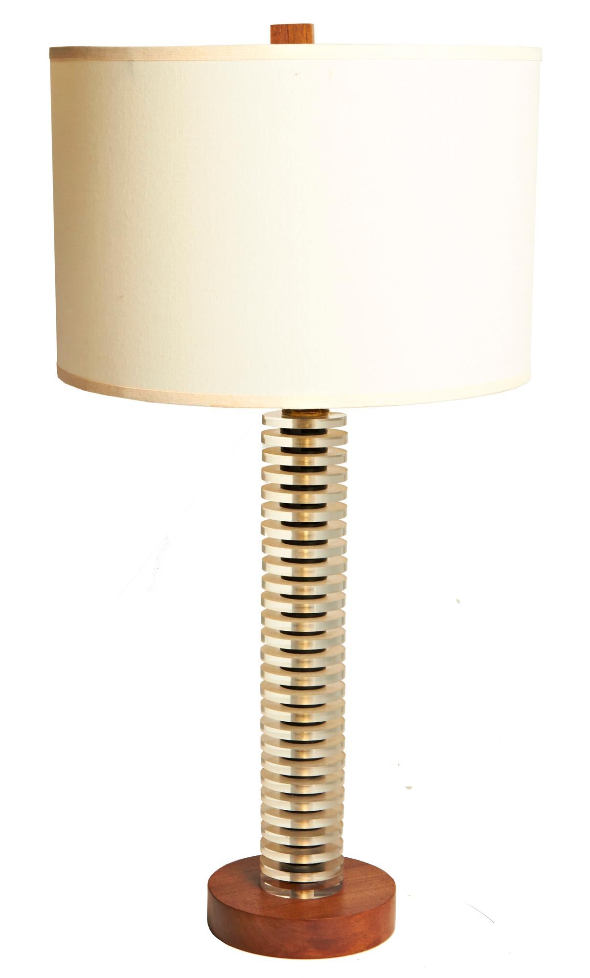 This elegant lamp has a wooden disk base on which is mounted a column comprised of 27 translucent Lucite disks separated by smaller shiny black Lucite collars. The cube shaped wooden finial co-ordinates with the wooden base and all parts of this