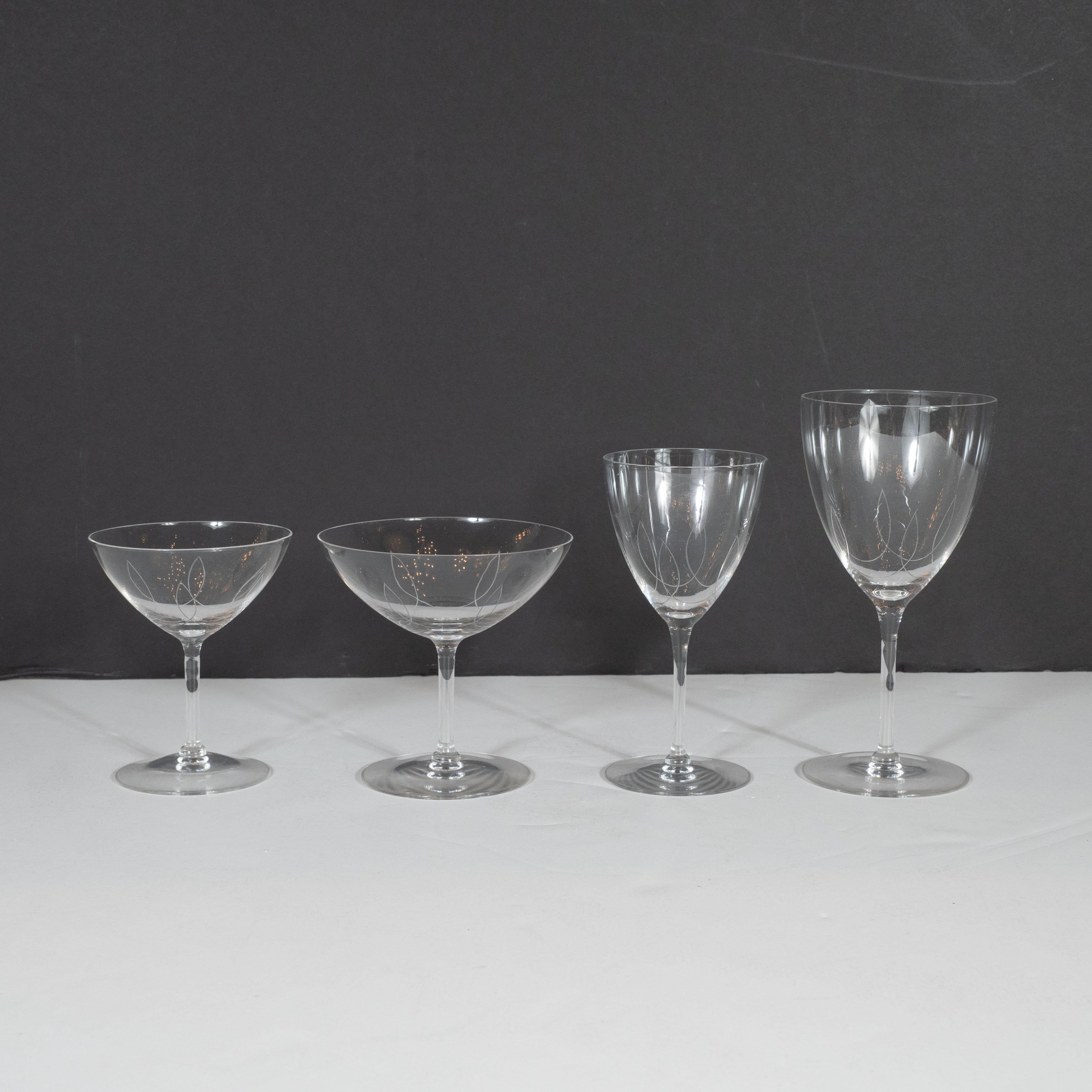 This elegant Art Deco complete set of eight glasses was realized in the United States, circa 1940. It features eight cocktail glasses, champagne coupes, wine glasses and water glasses, each etched with a curvilinear pattern running across the body