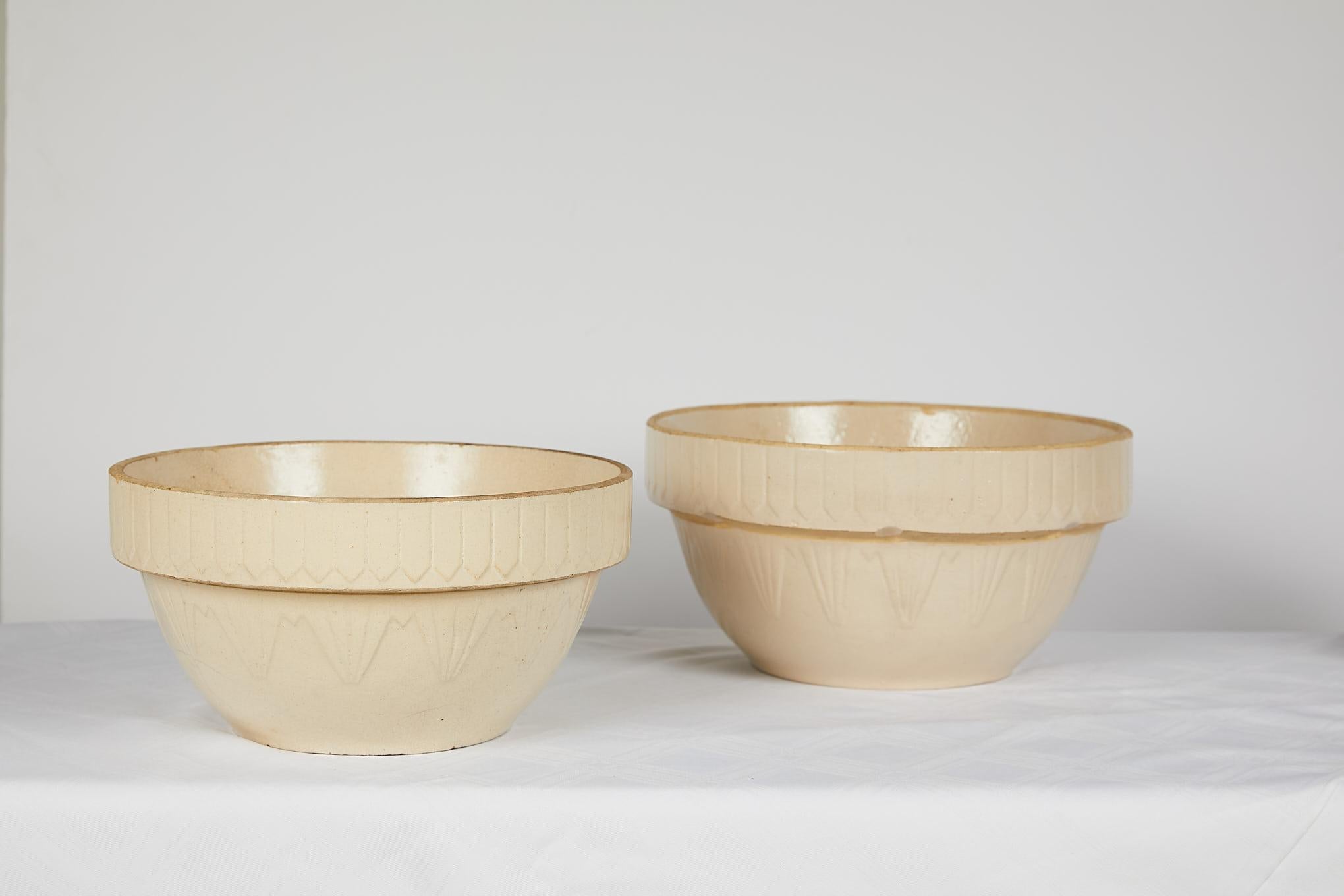 Early 20th century American Art Deco earthenware or yellow ware pottery nesting bowl set. The mixing bowls’ pattern is called the picket fence design because the decoration around the top looks like pickets. There are indentations around the rim of