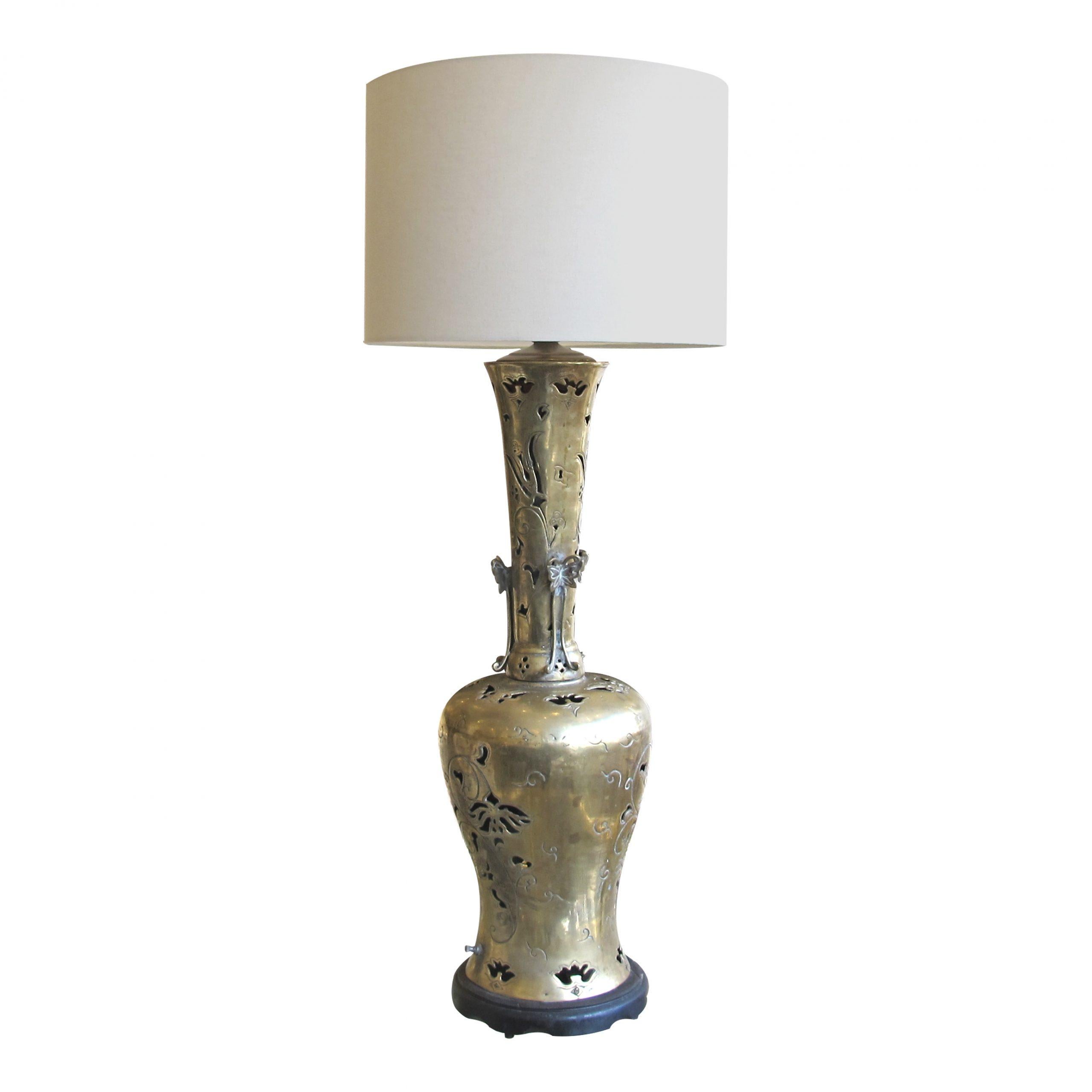 This is a rare large table lamp from around 1930. The lamp has generous and elegant curves and boasts delicate flower and butterflies’ carvings, the neck of the lamp shows three brass butterflies in relief. The lamp is presented on a black carved