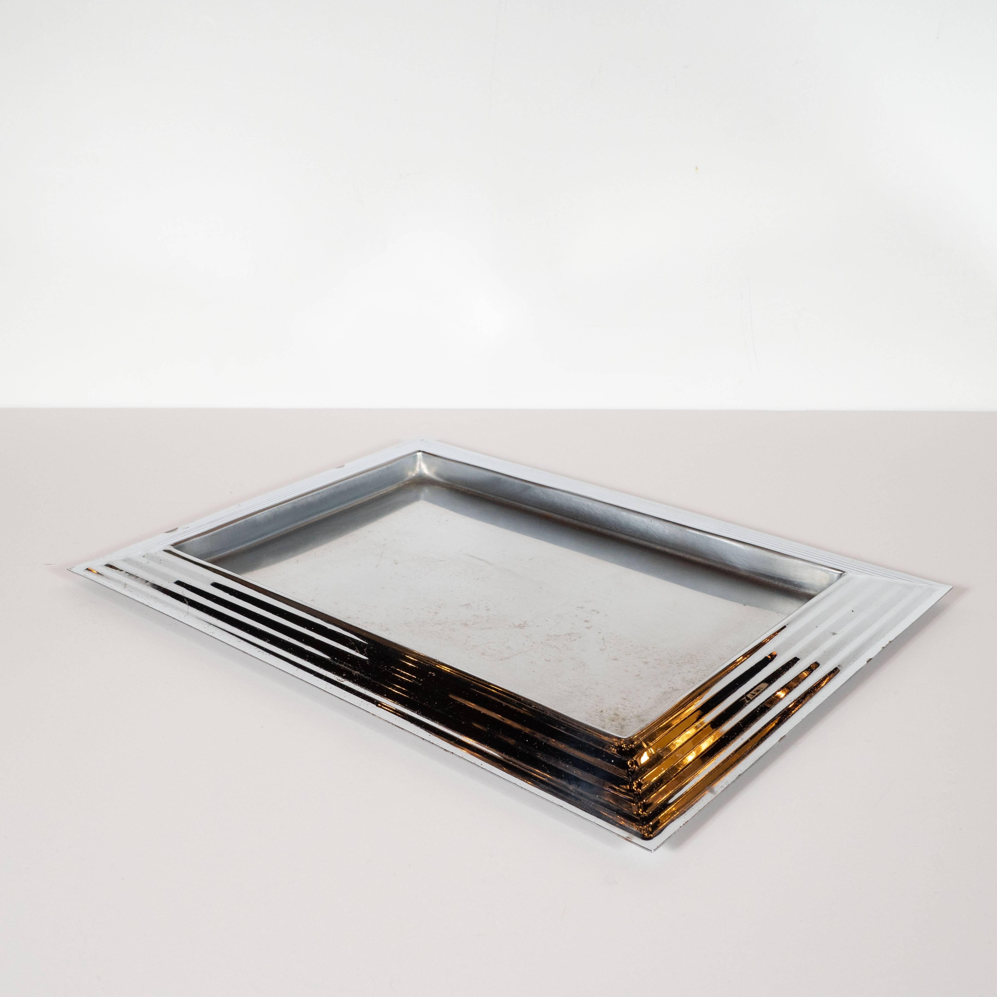 This handsome bar tray was realized in the United States, circa 1935, by the esteemed Revere Co. It features a rectangular form with a skyscraper style perimeter descending in height to the edge in banded steps. With its austere form and clean