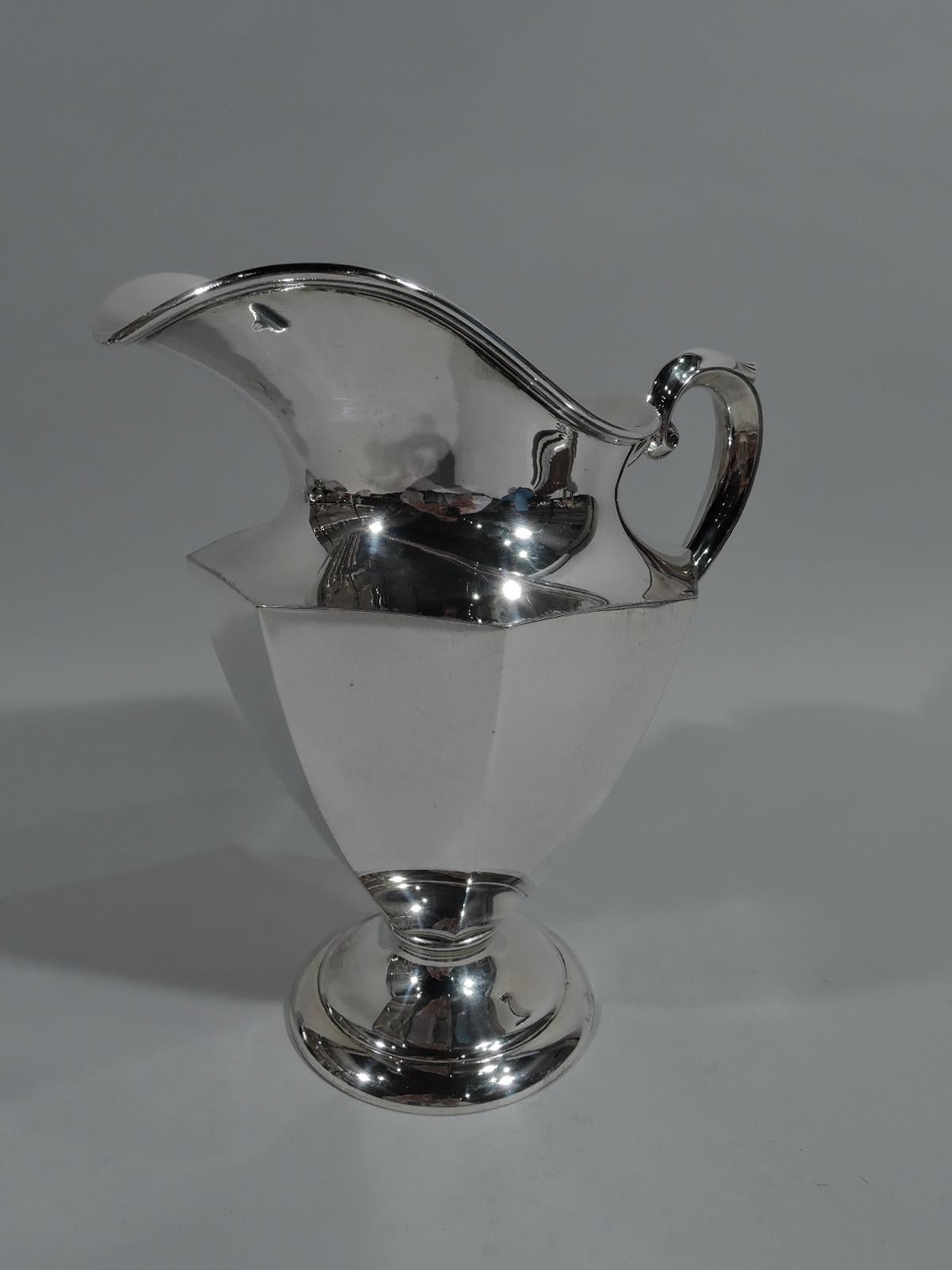 Art Deco sterling silver water pitcher. Made by M. Fred Hirsch in Newark, circa 1930. Faceted and tapering sides, helmet mouth with reeded rim. Scroll handle with stylized leaf cap, and stepped foot. Fully marked including no. 509. Weight: 28 troy