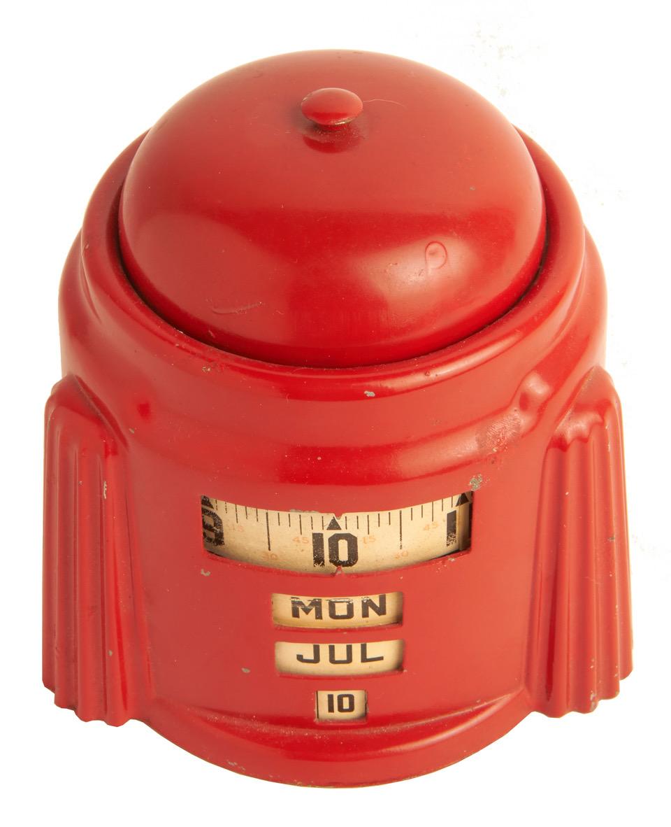 This American Art Deco Kal-Klock bright red enamelled, mechanical alarm clock with integral manual tape-measure type perpetual calendar was designed and patented (Des 110,489 please see below) by Herbert W. Lamport in 1938. It would seem that he