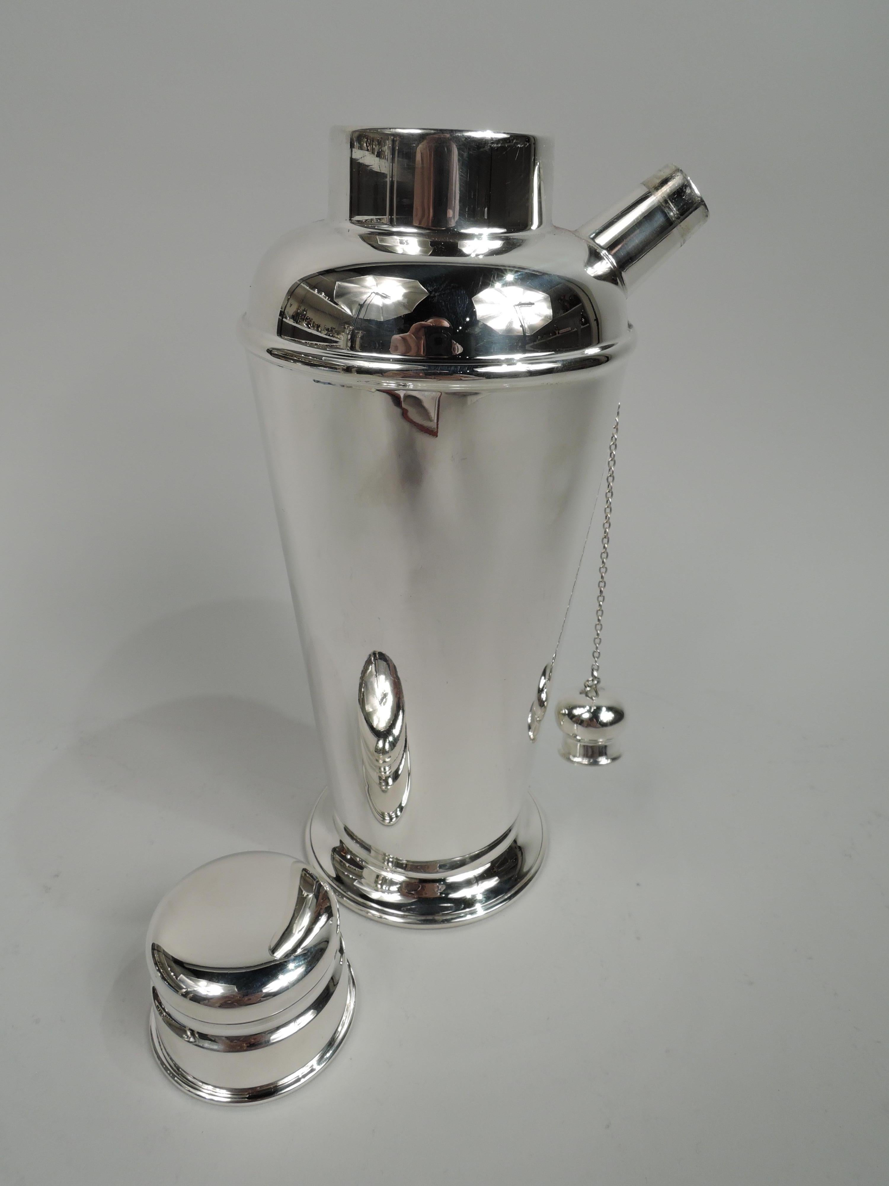Art Deco sterling silver cocktail shaker. Made by Currier & Roby in New York, ca 1925. Straight and tapering sides and skirted foot; curved shoulder, stubby diagonal spout with built-in strainer and chained cap, and inset neck with snug-fitting cap.