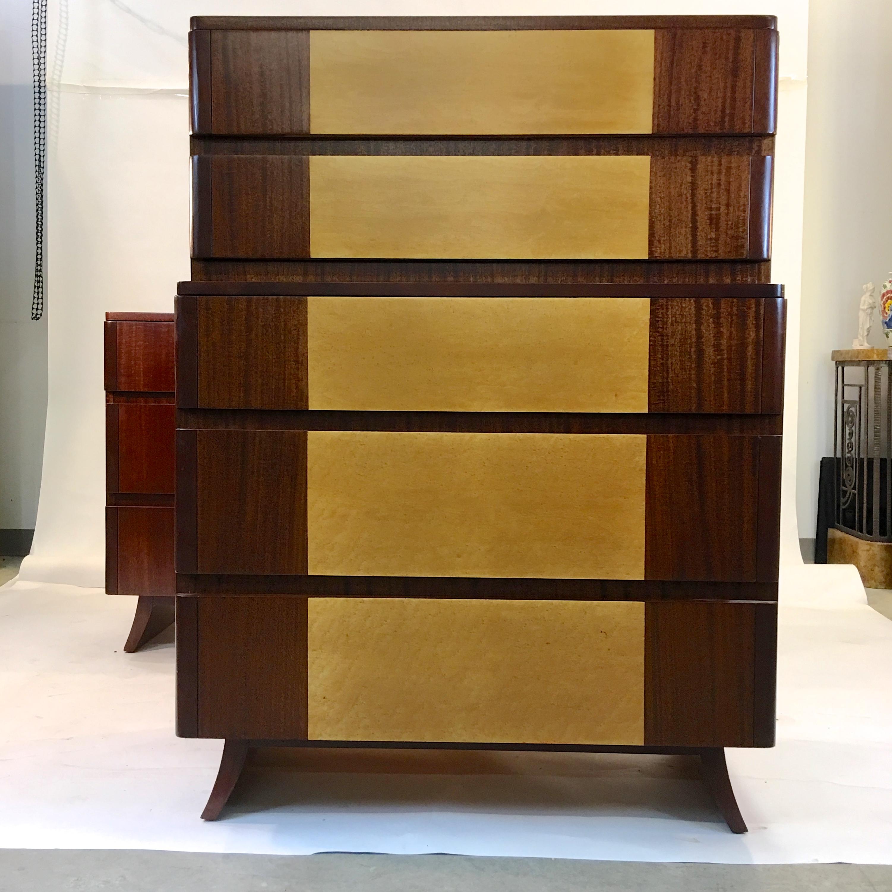 American Art Deco highboy dresser with Machine-Age lines in its tiered appearance and curved edge drawers. Produced circa 1947 by R-Way Furniture Co in the manner of Eliel Saarinen. Two tone bookmatched mahogany with exotic burl or curly maple inlay