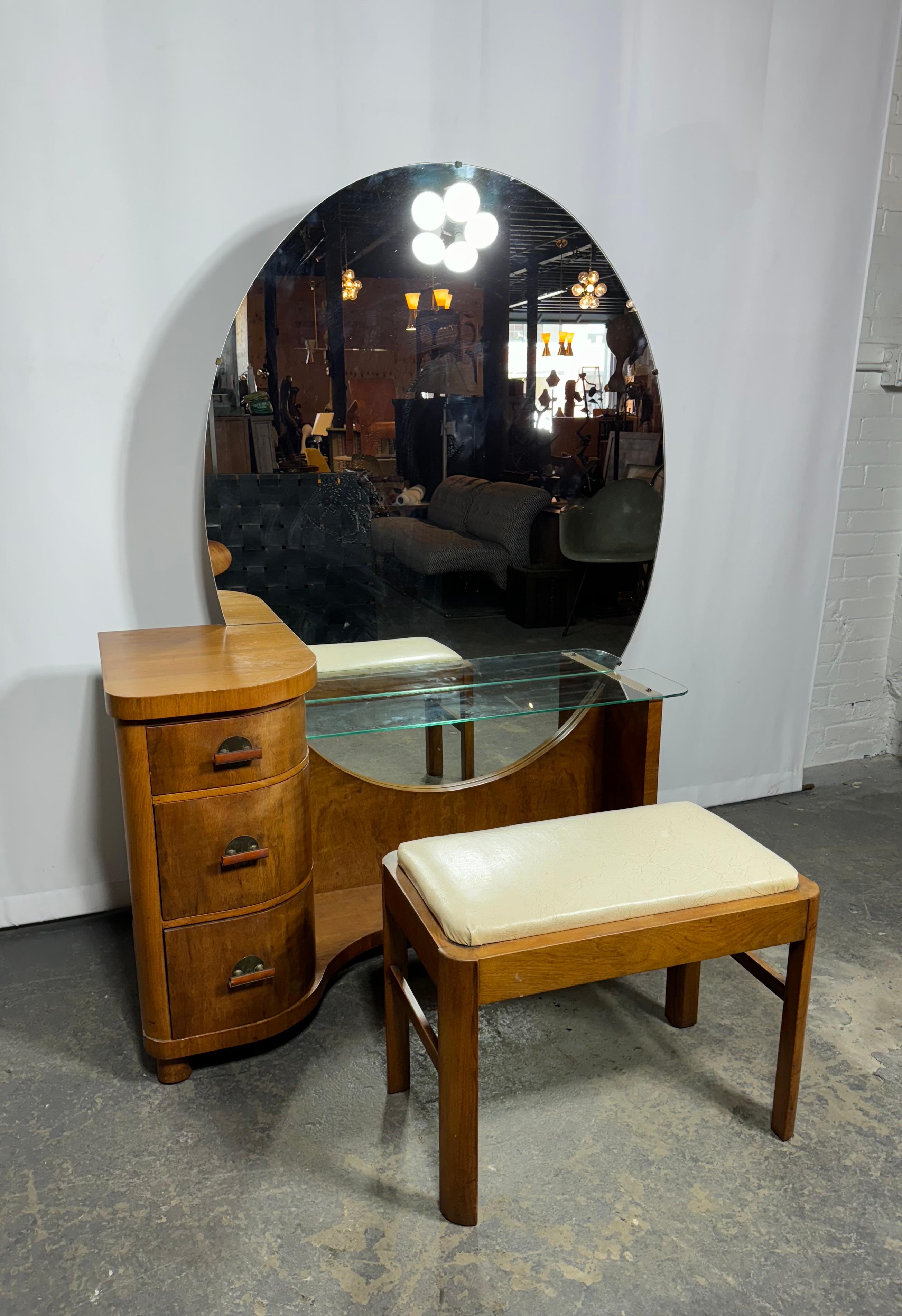 Classic American Art Deco Vanity /Dressing Table and bench by Henry STEUL & sons,, Superior quality and design. unusual oval mirror, brass and bakelite hand pulls.. Wonderful figured walnut wood,, 3-drawers, glass shelf,, Stunning design. Hand