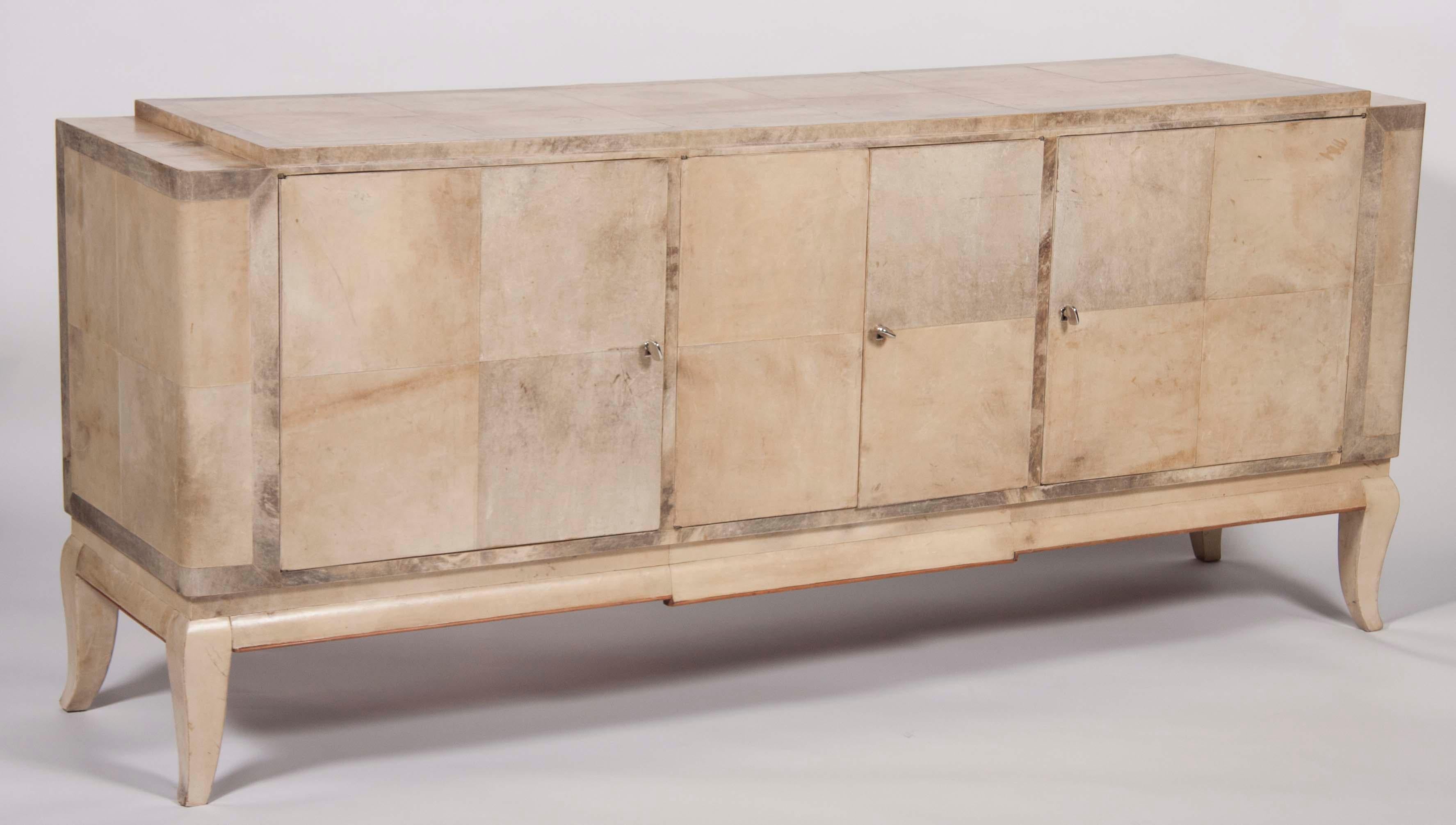 A stunning 1940s credenza covered in parchment, with thin fruitwood molding along the base. Very much in the style of, and possibly created by the American designer Samuel Marx. The variegated shades of the parchment give this piece a distinct and