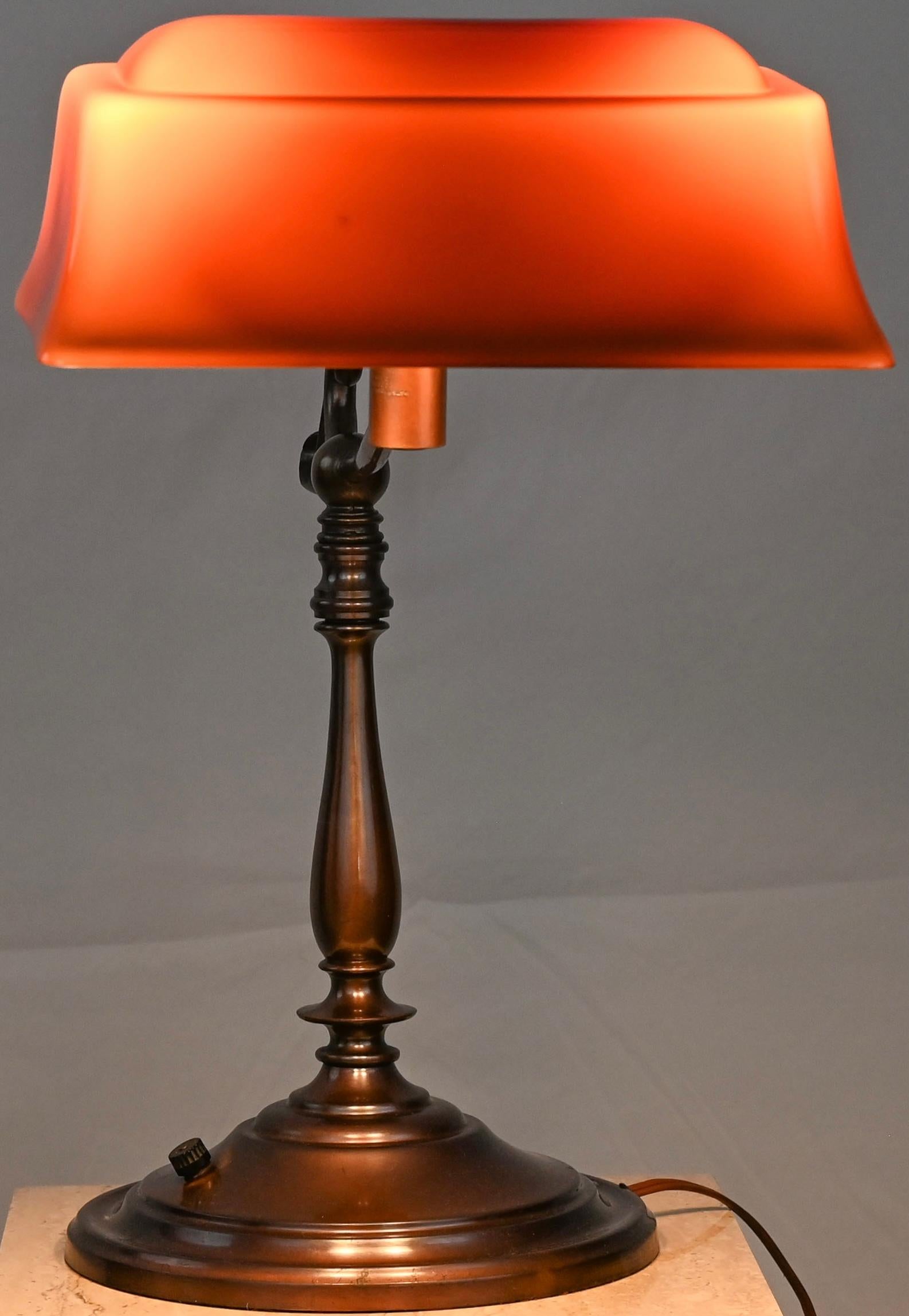Eine atemberaubende amerikanische Art Nouveau Emeralie Tischlampe oder Schreibtischlampe mit ihrem originalen Schirm. Diese prächtige Bankierslampe / Emeralite mit rot / orangefarbenem Opalglasschirm und Messingfuß wurde um 1900 hergestellt. Es ist
