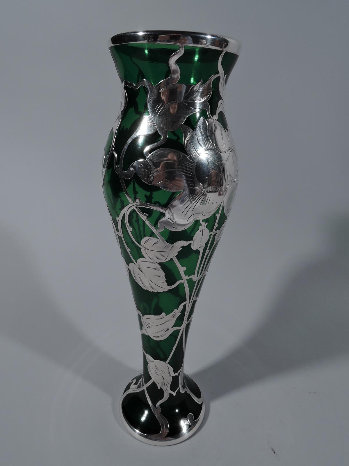 Turn of the century American Art Nouveau green glass vase with engraved silver overlay. Narrow and graceful baluster overlaid with loose, semi-abstract flowers and entwined stems. Armorial cartouche engraved with script monogram.