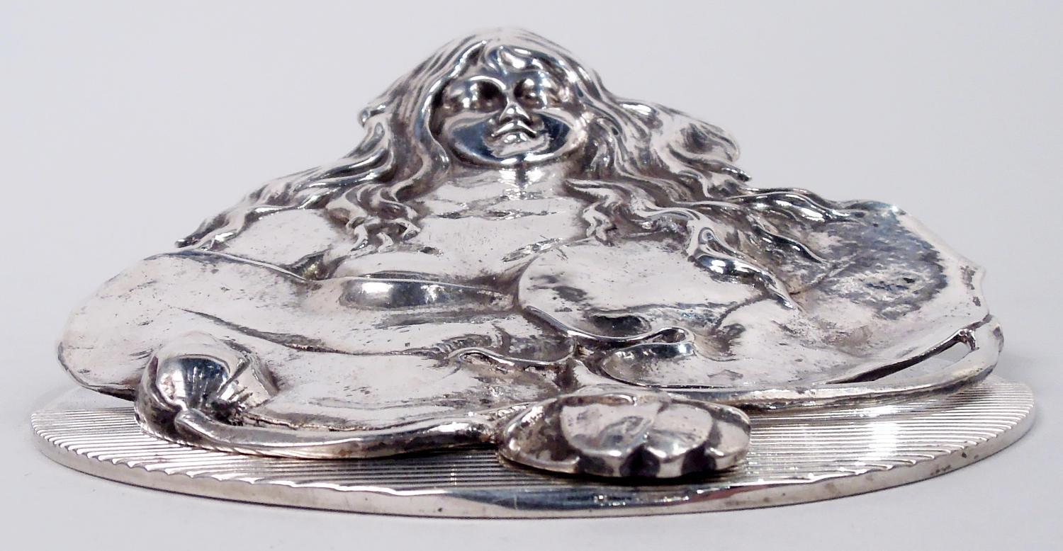 Art Nouveau sterling silver paper clip. Made by Graff, Washbourne & Dunn in New York, ca 1900. Long-tressed nymph emerges from the water with bosom concealed by waterlily pads. In relief. A wonderful period piece, though a possible distraction on
