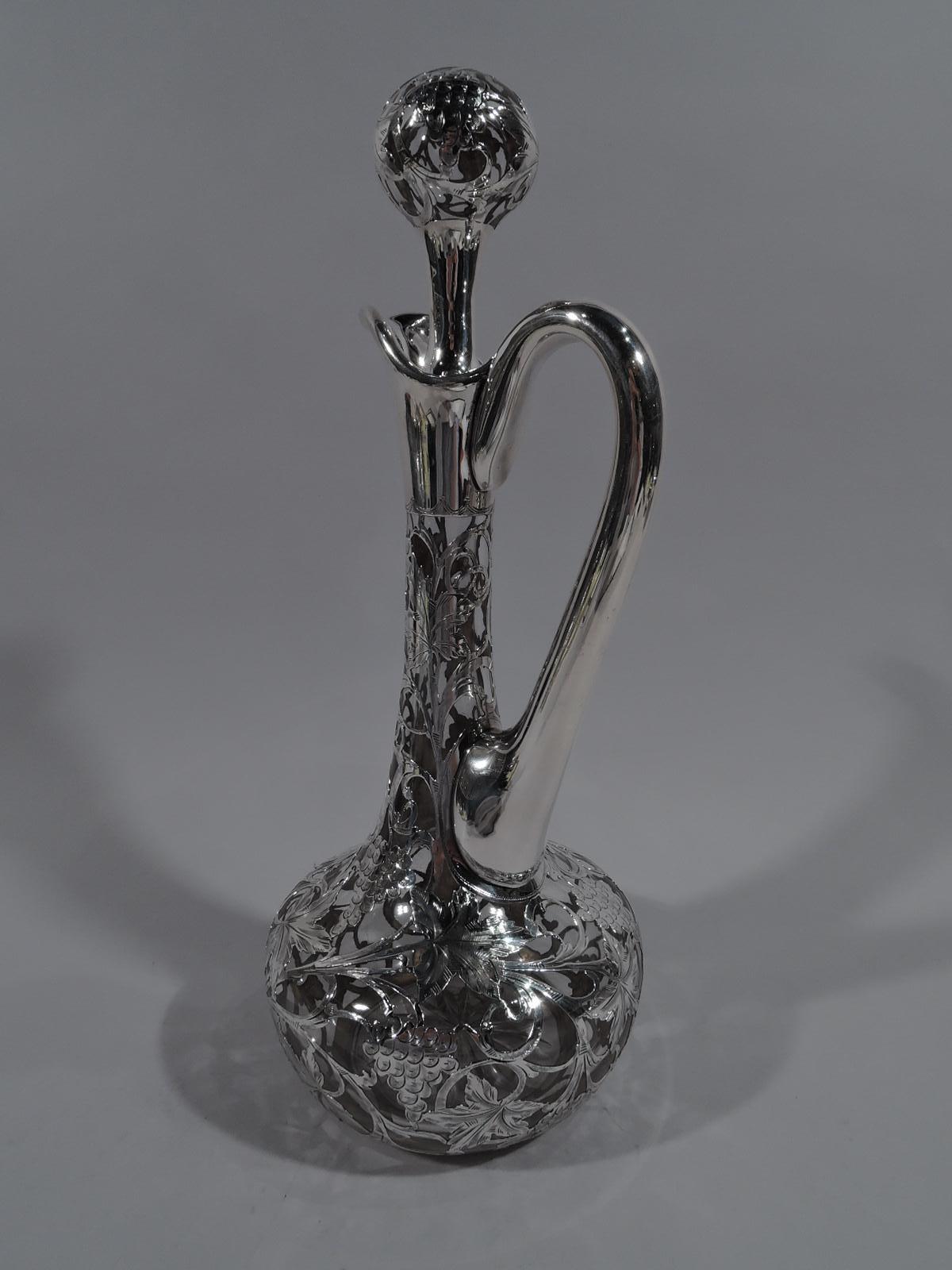 Turn of the century Art Nouveau clear glass decanter with engraved silver overlay. Made by Alvin in Providence. Globular body with high-looping handle, upward tapering cylindrical neck, and helmet mouth. Ball stopper with short plug. Dense and