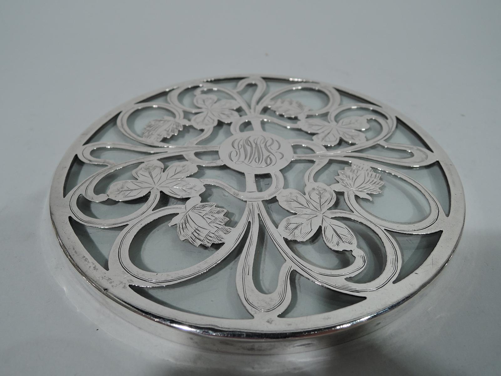 Art Nouveau glass trivet with silver overlay. Clear and circular with loose overlay inform of whiplash tendrils, leaves, and buds. Central circular frame engraved with interlaced script monogram. Hallmark includes no. and stamp for The Merrill