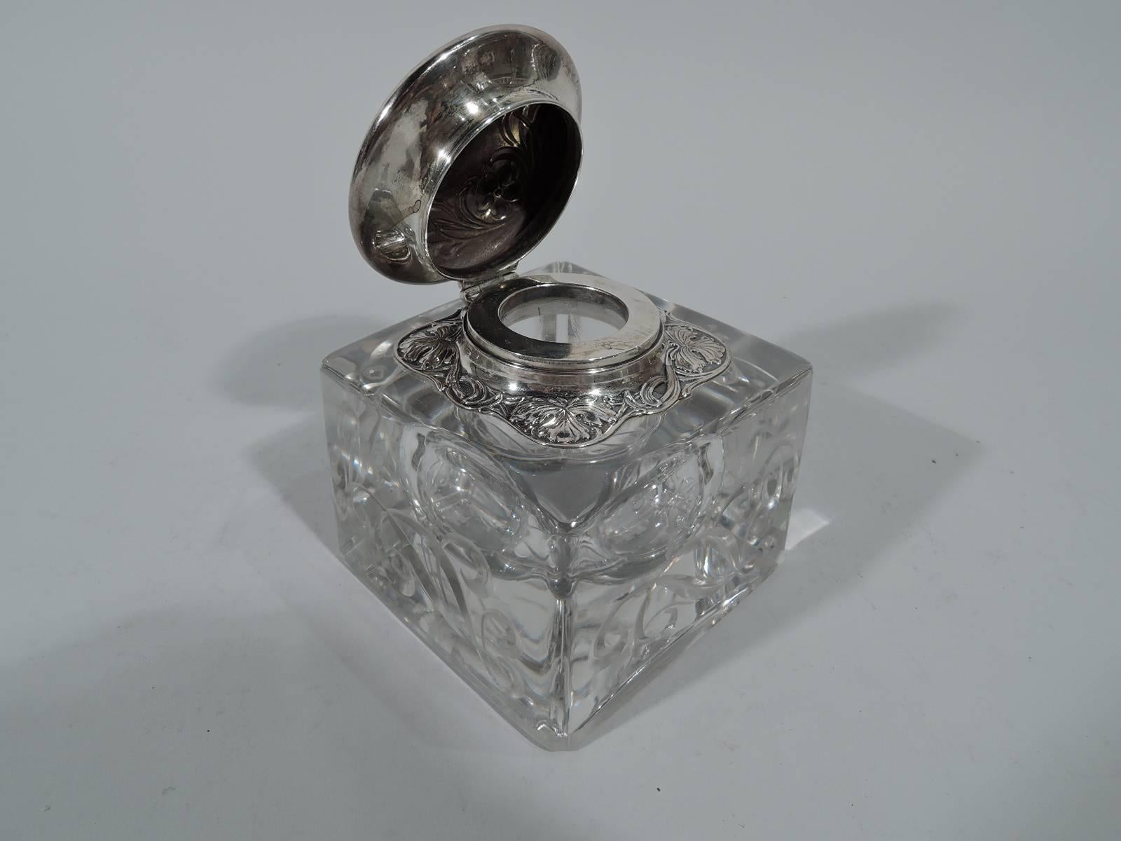 Art Nouveau glass and sterling silver inkwell. Made by Gorham in Providence. Rectilinear clear glass block bulbous well. Sides have carved ornament: Fluid scrollwork and stylized flowers. Short neck in sterling silver collar surrounded by squarish
