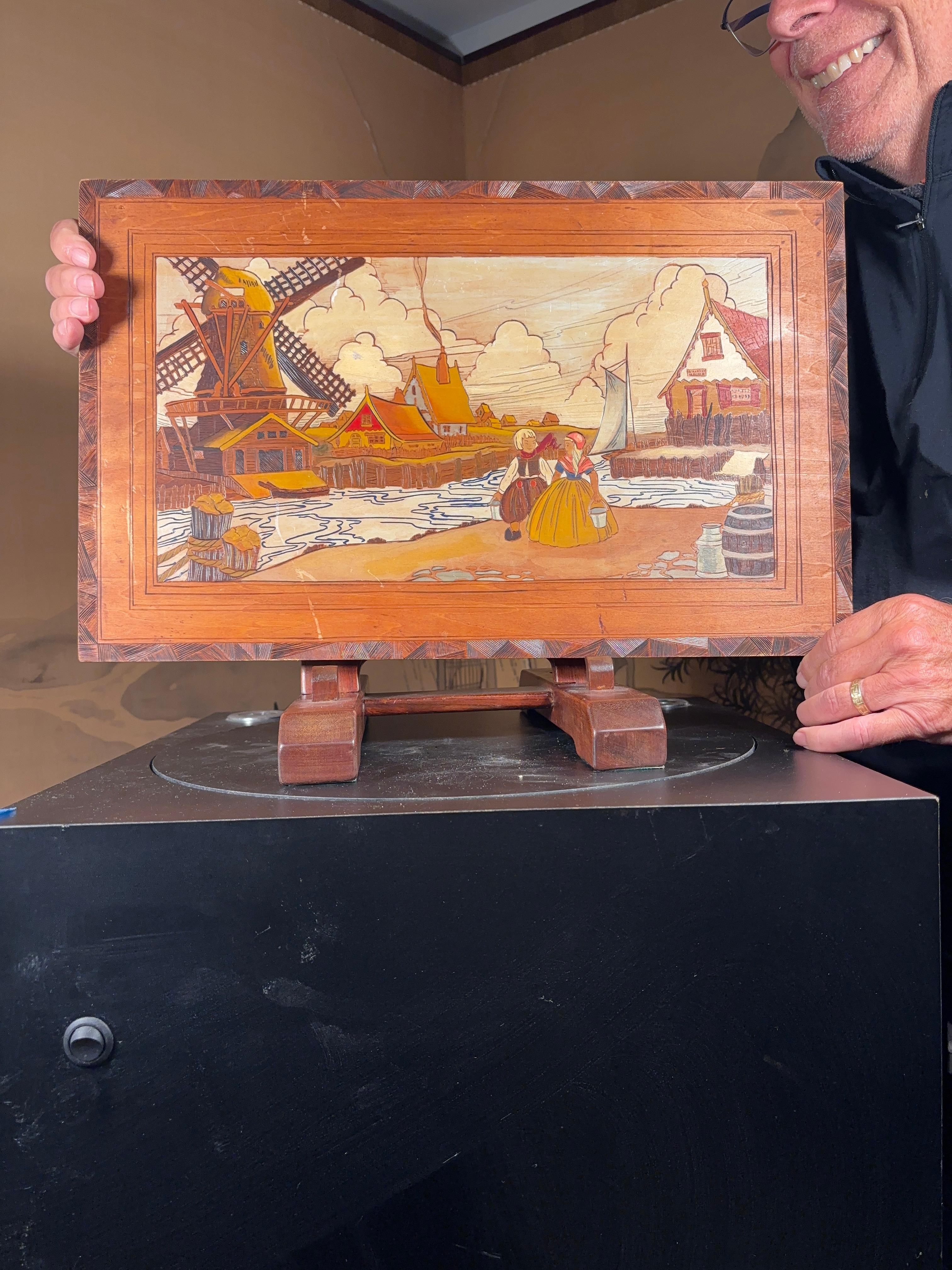 
An unusually fine mid century Arts and crafts pyrography portrait of two Dutch children amidst a scene of a windmill , home, boat and water.
Attractively hand stained or painted with a handsome frame like outer border.

Excellent quality for this