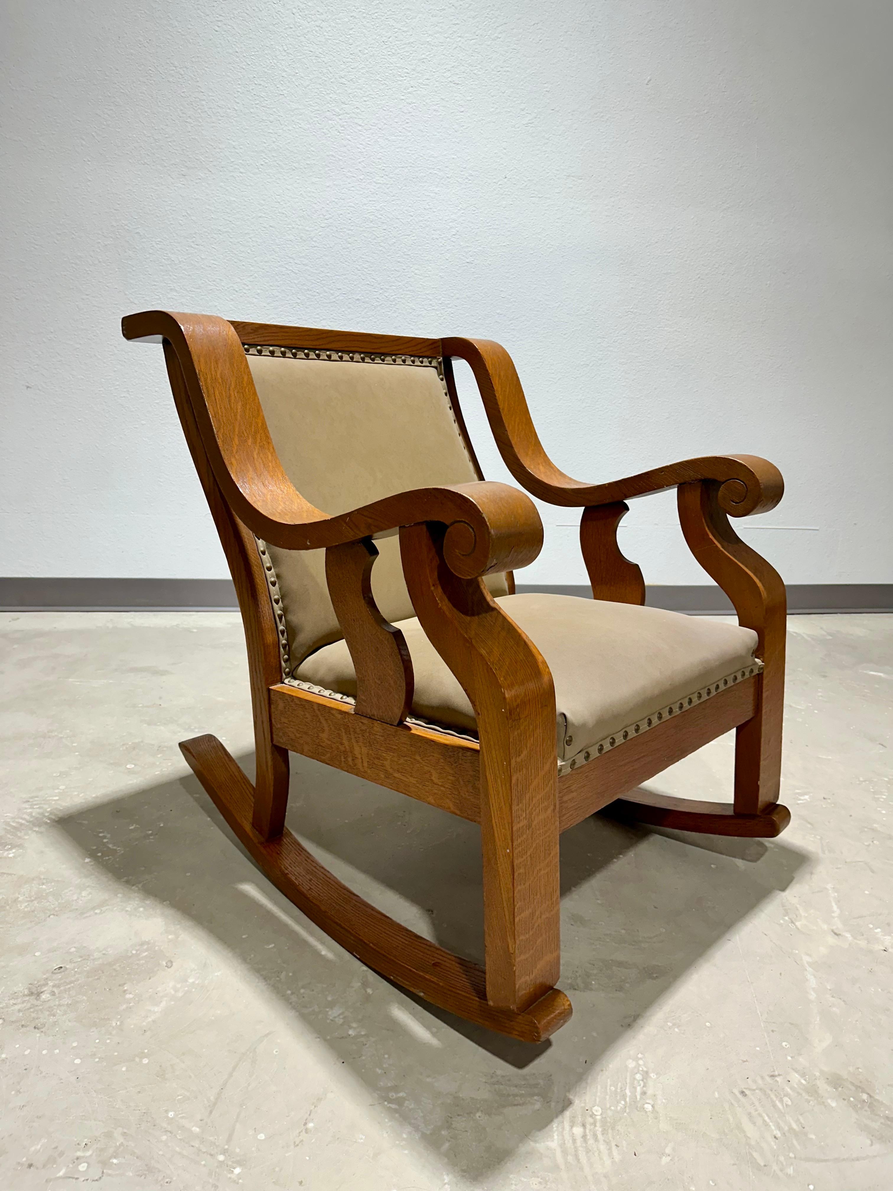 Pair of American 1920’s Arts and Crafts style Quarter Sawn Oak Scroll Arm Chairs. Rocking Chairs and Matching Armchair in solid oak with heavy duck canvas taupe upholstery with nailhead detailing. A handsome and comfortable pair that would blend