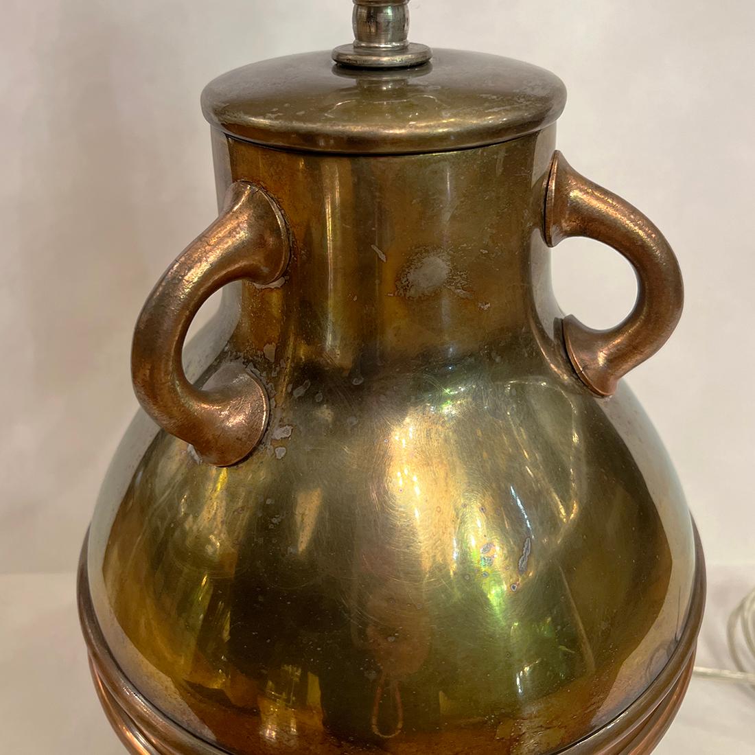 Lampada da tavolo in bronzo e rame del 1920 circa, finitura originale, a forma di urna con tre maniglie. 

Misure:
Altezza del corpo: 12.25
