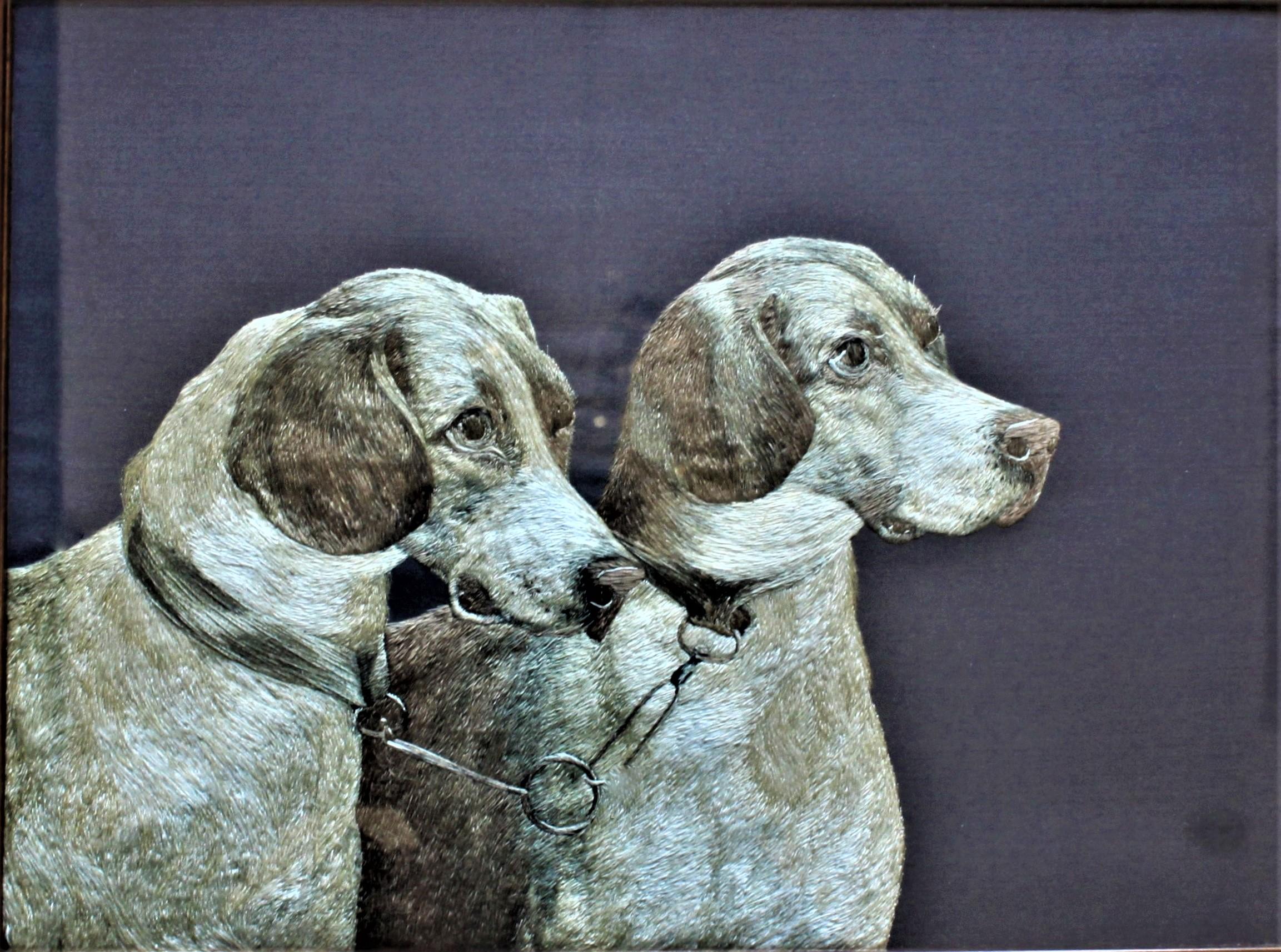 Presumed to having its origins in the United States and done in the Arts & Crafts period, this extremely intricate and realistic depiction of two hound dogs bridled together is done completely in various colors of silk thread. The faces and bodies