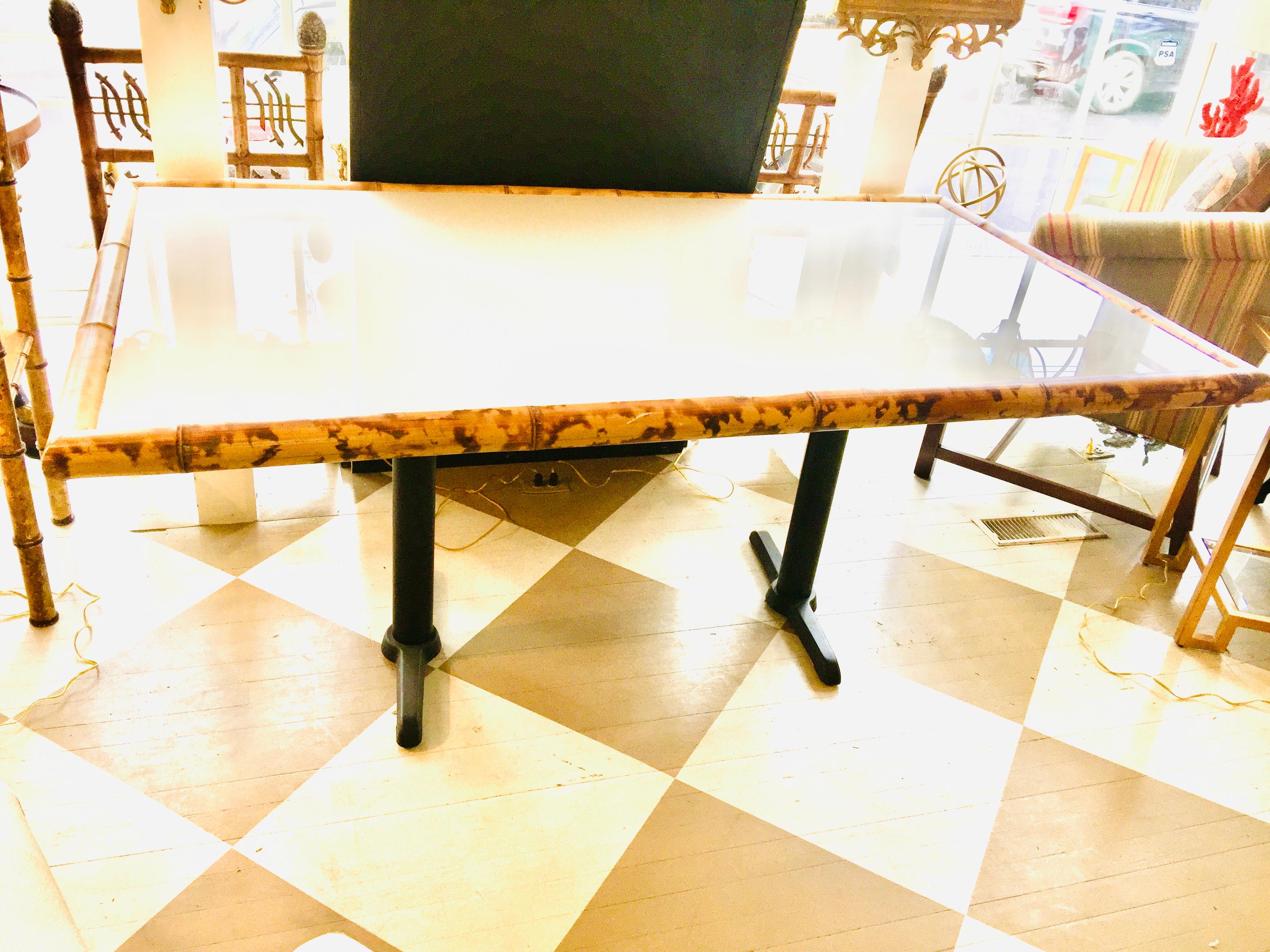 American center table, dining table, or writing table; Having a colorful thick bamboo
Trim around a white wooden top on a metal base. There is a white milk glass on top of the wooden top setting in the bamboo trim. The two legs are charcoal black