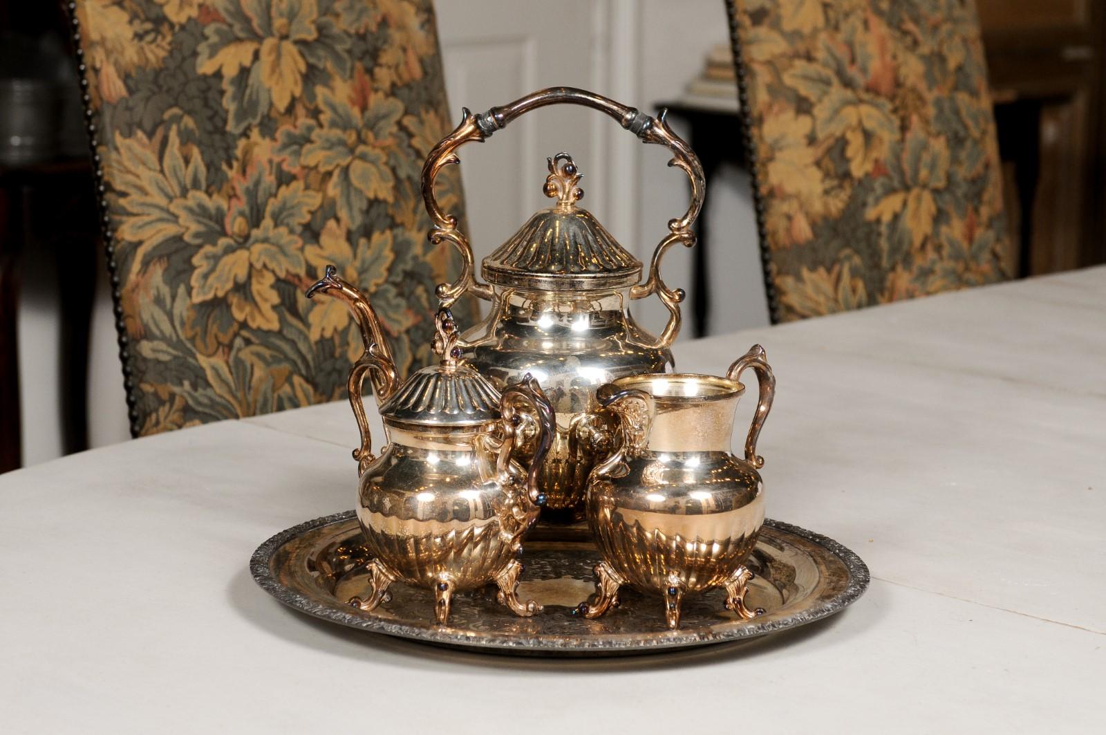 An American three-piece Birmingham Silver Company tea set from the mid 20th century, with scrolling accents. Created by the Birmingham Silver Company in the 1960s, this set features a teapot (10