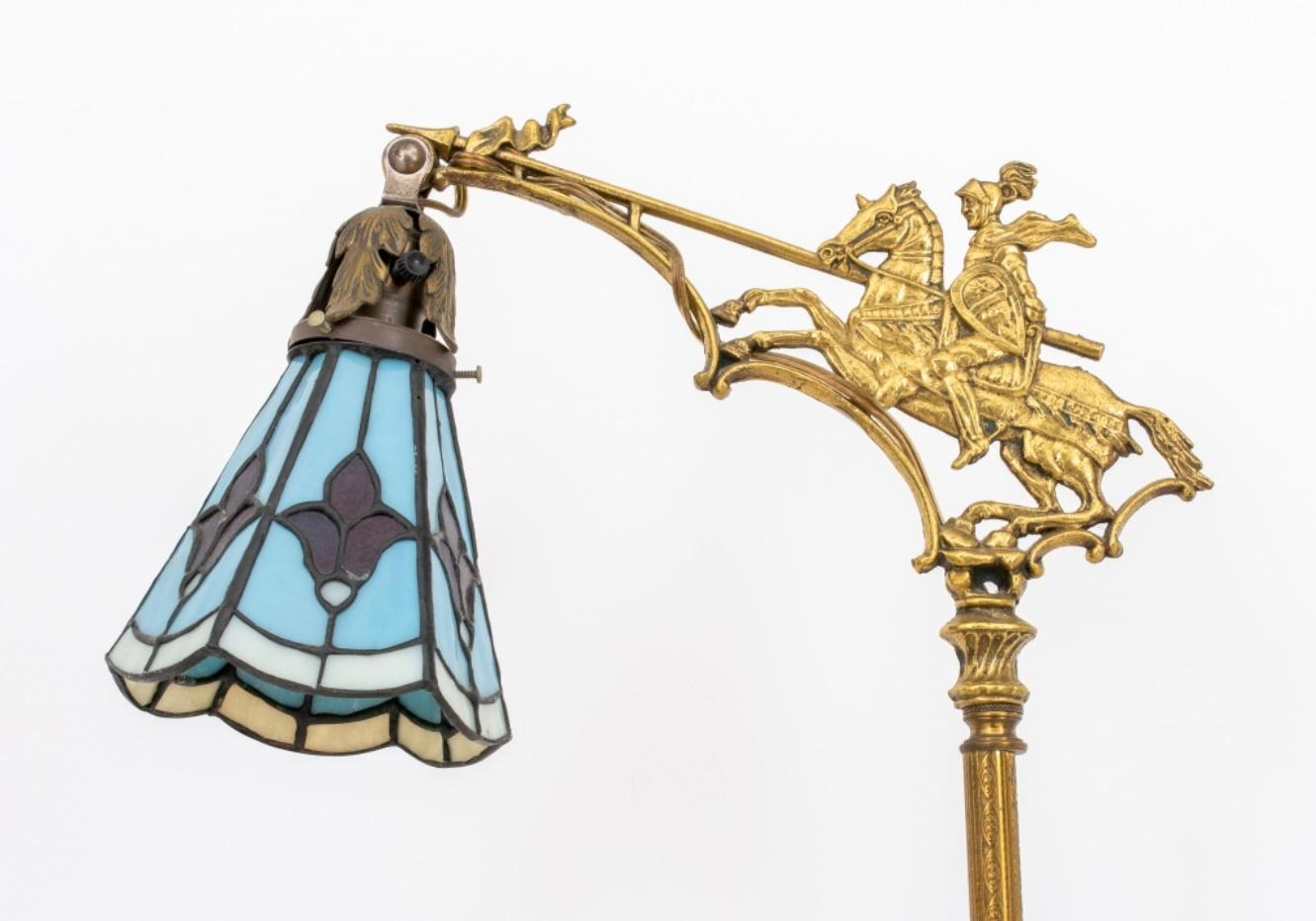 American Brass and Stained Glass floor lamp, 1910s-1920s, the brass column support with onyx spacers and base, the top with a figure of St. George and the Dragon as an angle to support the stained glass trumpet form shade. Measures: 61