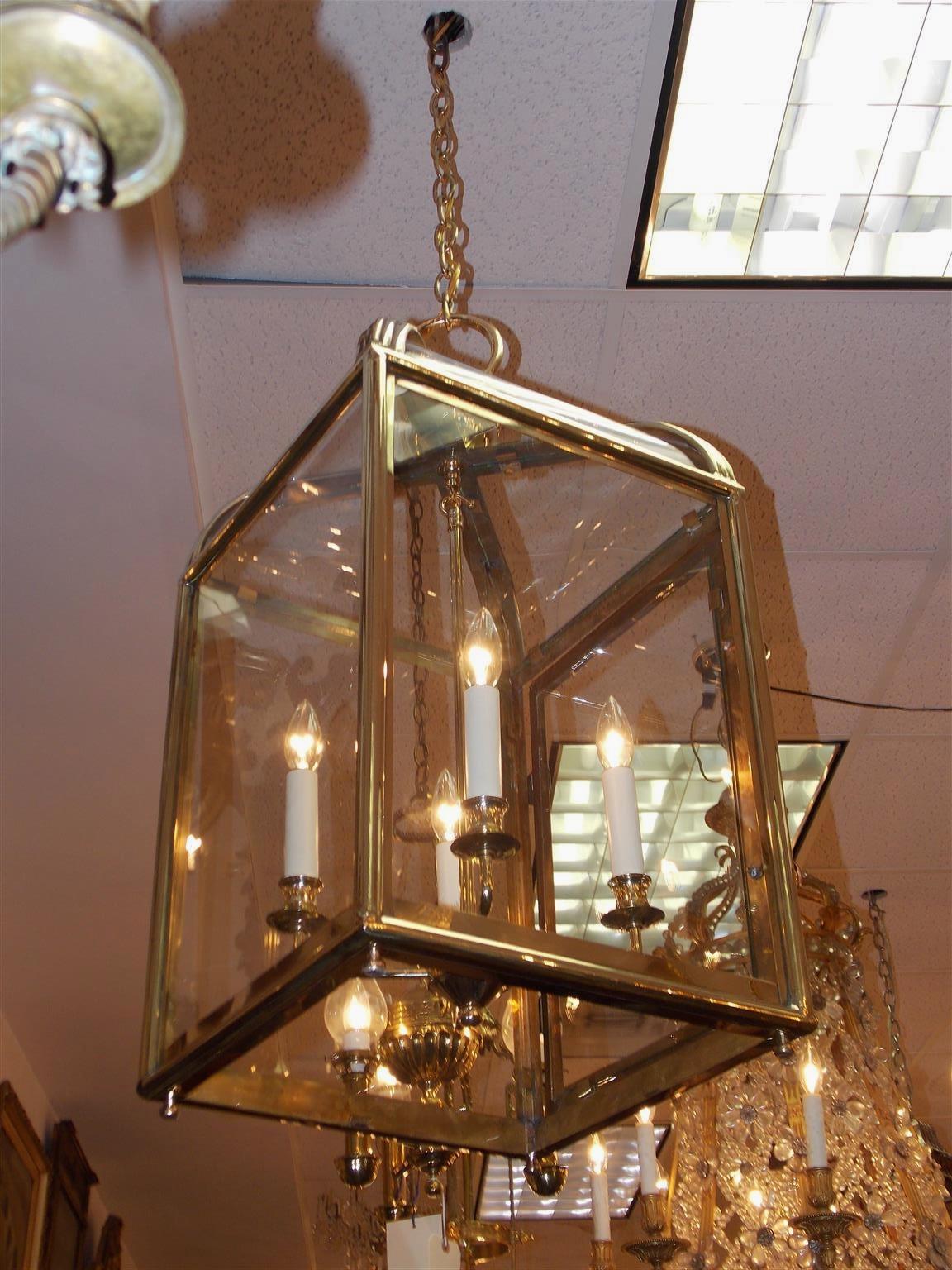 American brass glass dome hanging lantern with a centered circular sphere ring, fluted exterior border, hinged locking door revealing four-light interior cluster, and resting on four bun finials. Lantern was originally candle powered, Late 19th