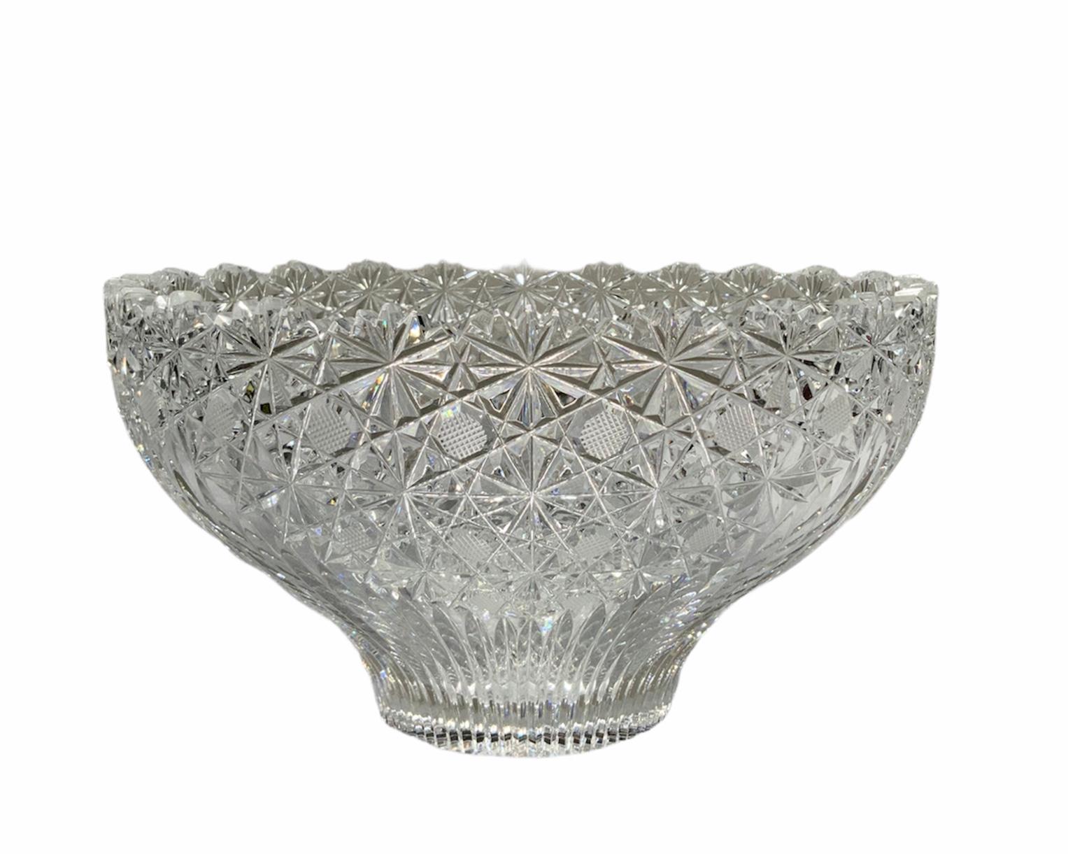 This is an American Brilliant cut glass crystal bowl adorned with stars and hobstars formed by geometric triangles. Strawberry diamonds are in the center of the hobstars. The rim is scalloped. Inside the bowl, there is a large trefoil made with