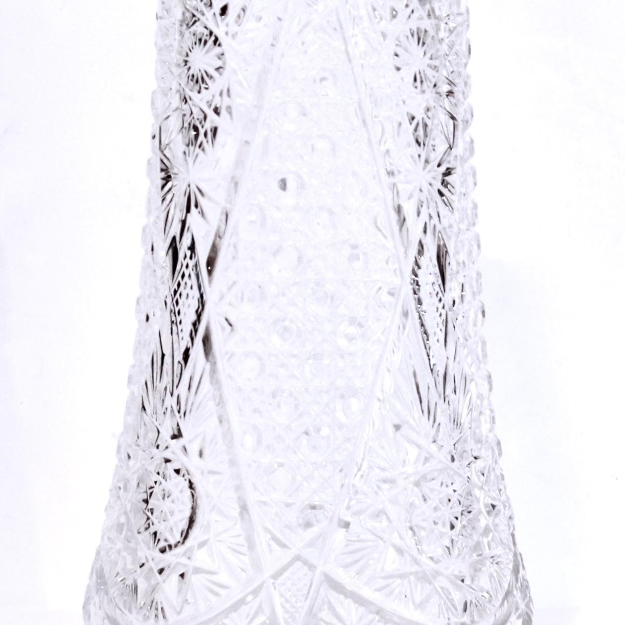 Un joli vase à fleurs en verre facetté de bonnes dimensions, décoré d'un bord en dents de scie, sous lequel se déploient des motifs complexes de tourbillons et d'étoiles, ainsi que d'intéressants motifs de facettes plates et de bosses. Deuxième