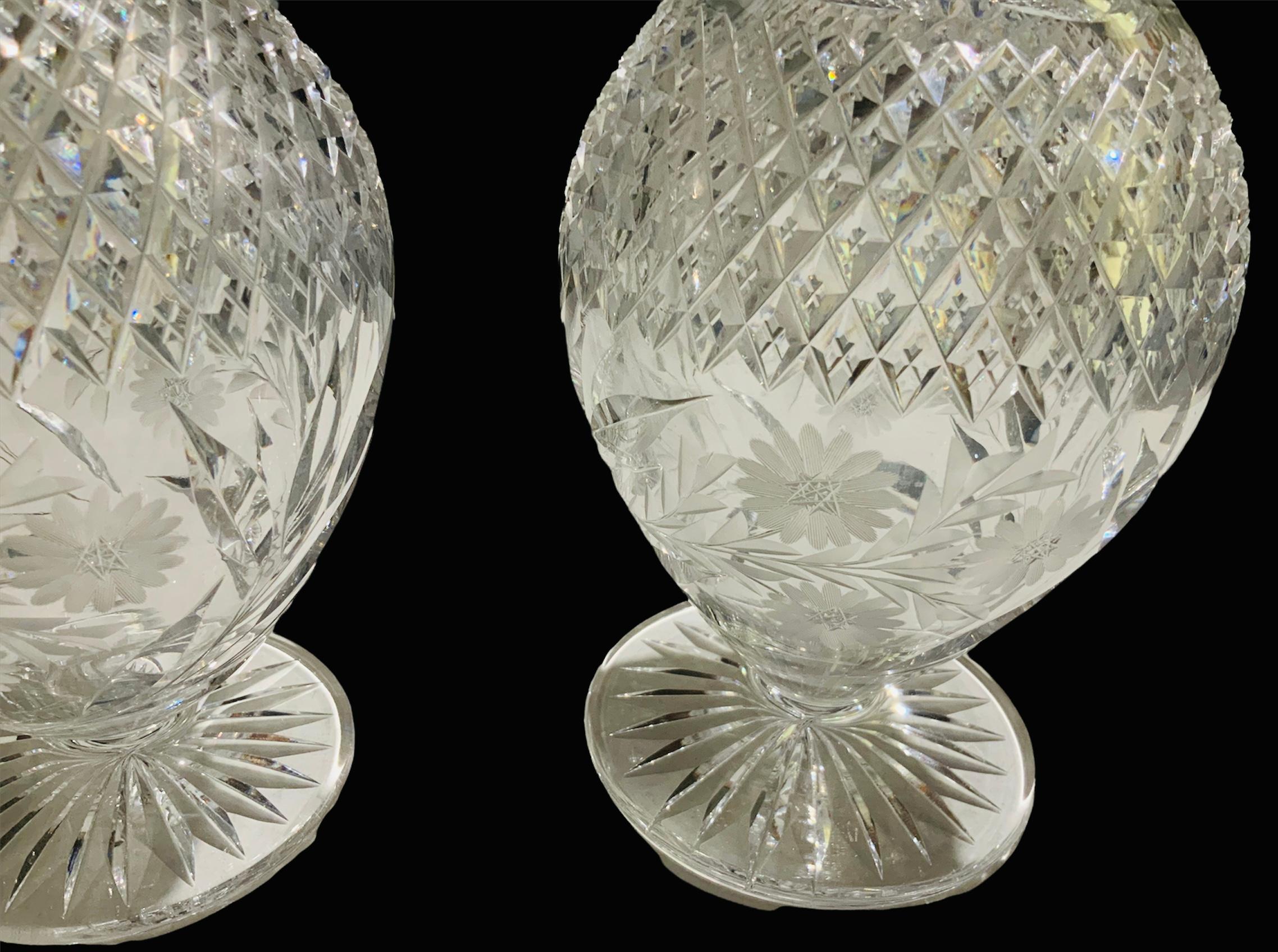 This is a pair of heavy cut clear crystal decanters. They have a long neck with a bulbous shaped body. Their neck is adorned with the knotched prism pattern. The upper body is highlighted with a diamond pattern cut and below it, there are an etched
