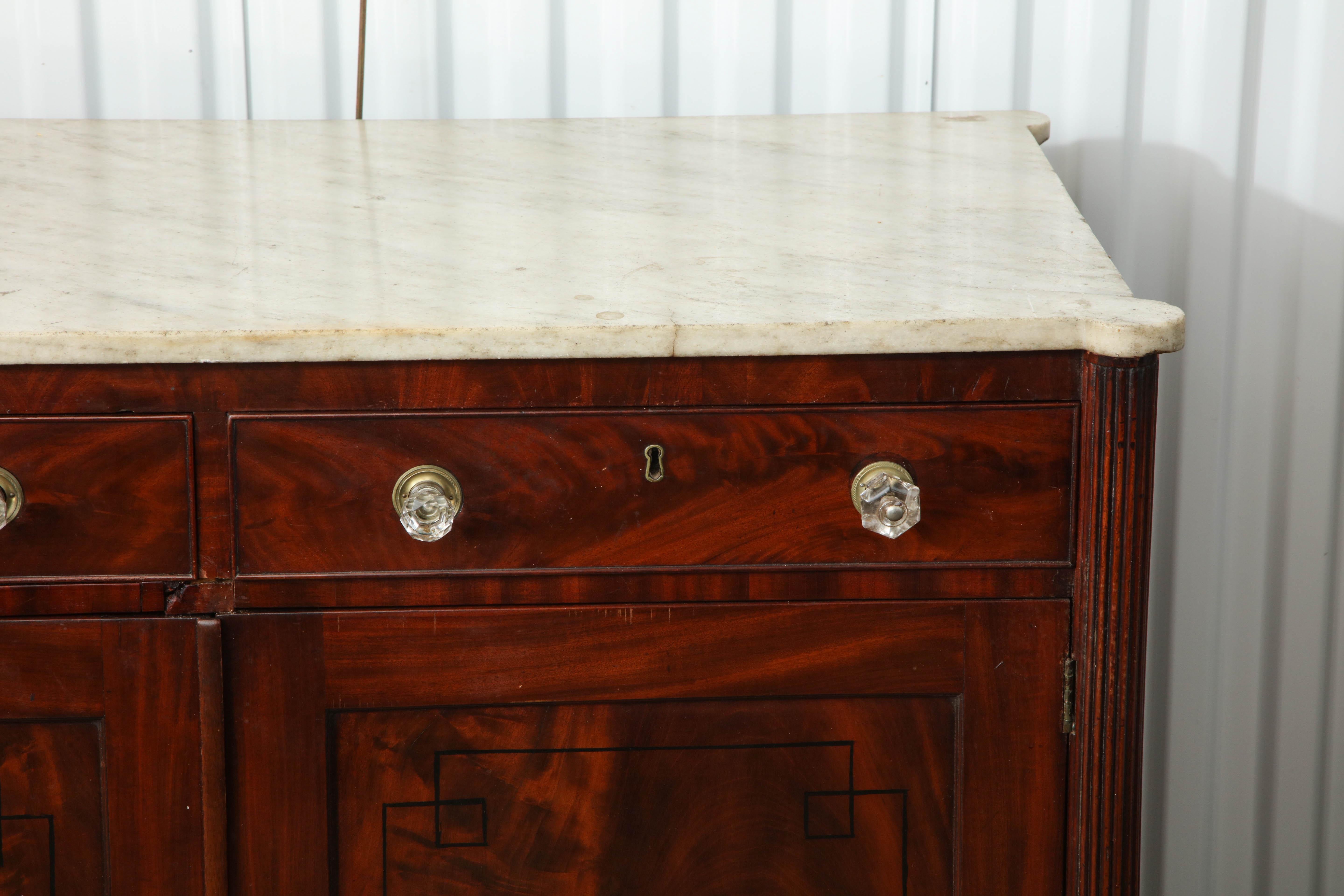 American New York marble top two-door mahogany cabinet with ball feet, turret corners and reeded supports.