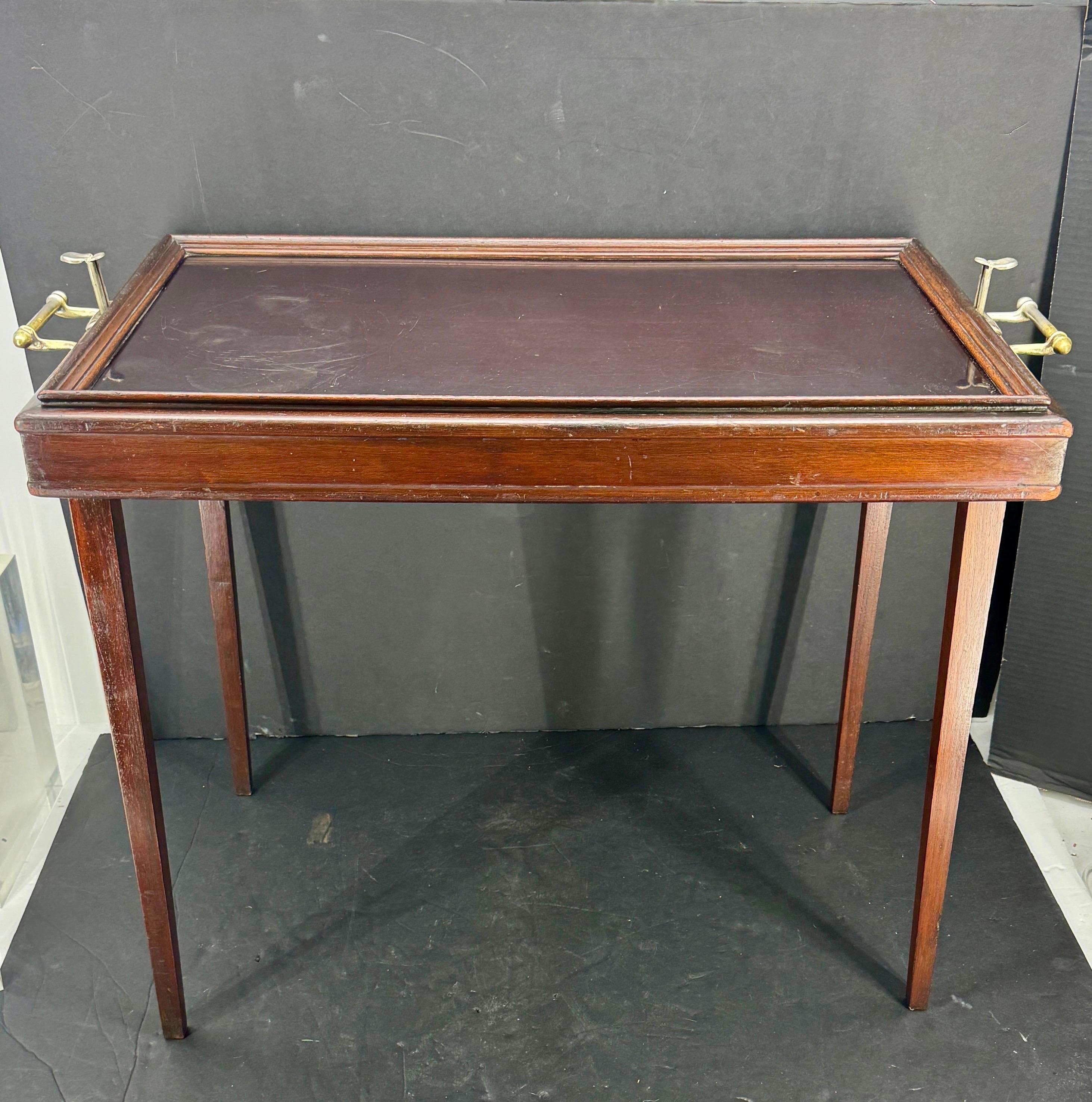 This R.R. Scheibe Tray Table is a beautiful antique piece, perfect for any room. The table is made of mahogany wood and black metal tray surface, giving it an elegant look. The handles are coated brass, making it easy to move around, and the table
