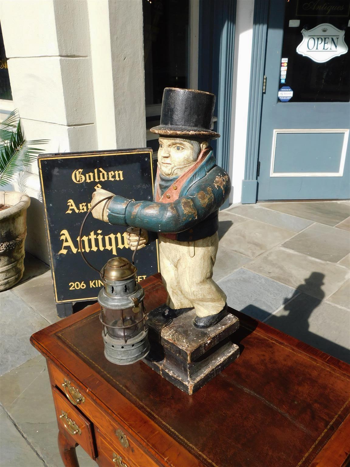 American Folk Art carved wood and painted ship officer on watch standing on a two tiered squared plinth with a brass and galvanized ship lantern hanging from wrist. Late 19th Century.