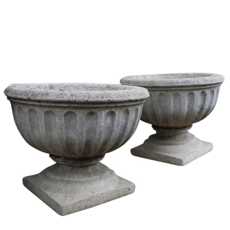 Available individually or as a pair, these matching urns feature a ribbed chalice on plinth design and a chic patina of age and wear.