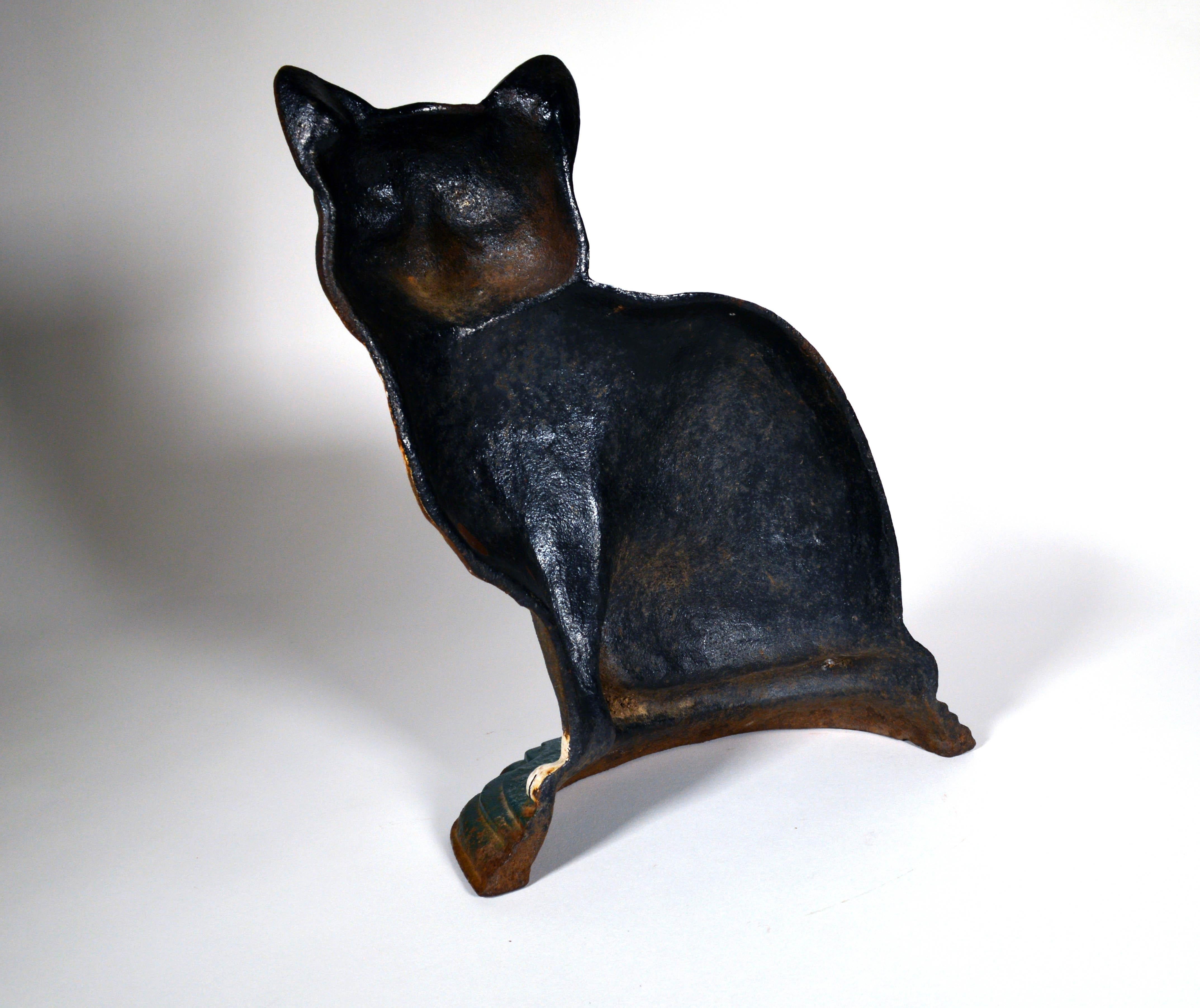 American cast iron cat door stop in form of a cat,
Early 20th century 
   


The American cast iron door stop is in the shape of a cat with reverse painted glass eyes and sitting on its haunches with its tail curled in front, and cold painted