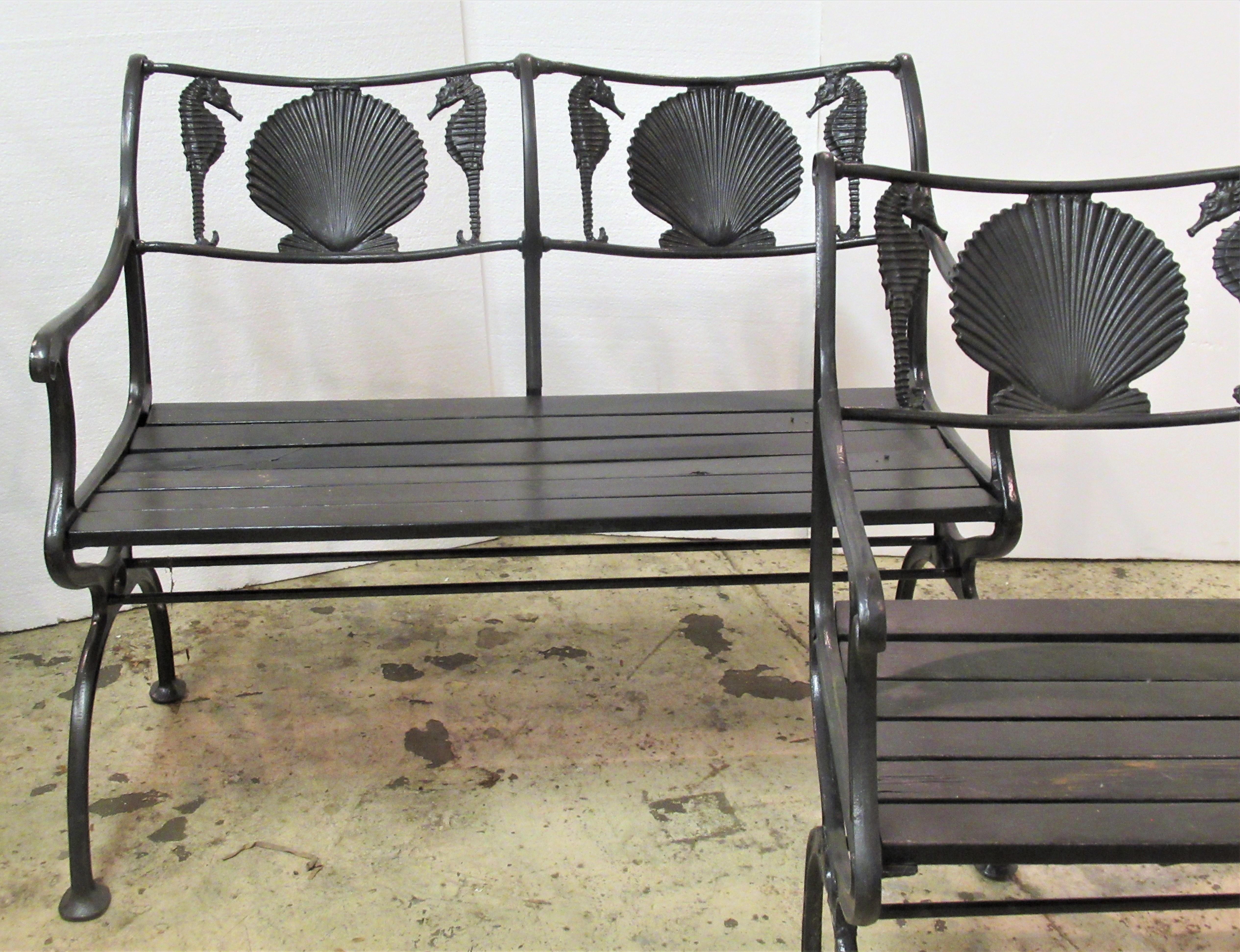Two matching antique American black painted cast iron garden benches having curved arms, wood slat seats and finely detailed sea horse with scallop shell designs at back rails. They are signed at upper sides Marcy Foundry - NY, NY patent dated 1930.