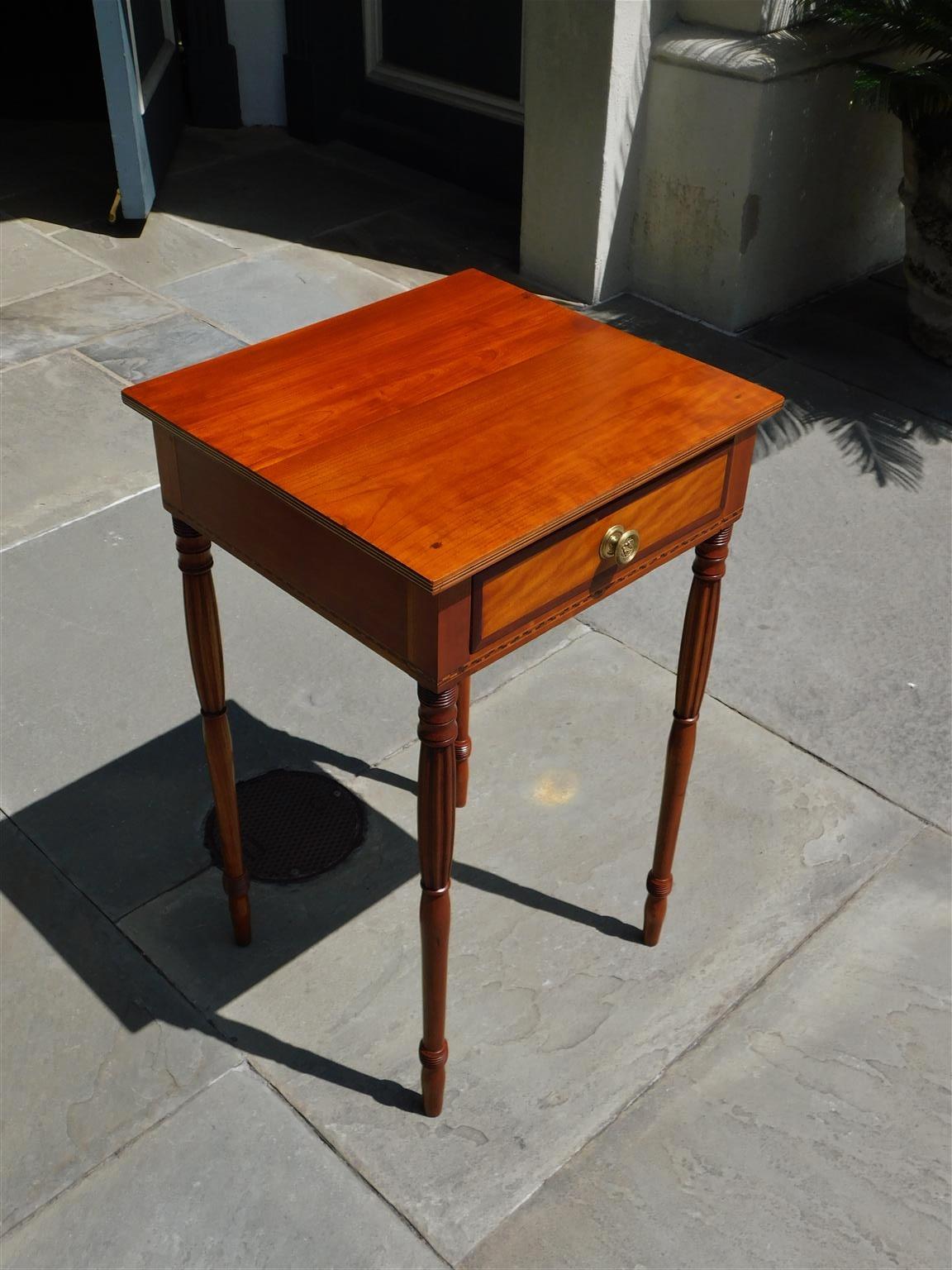 American Federal cherry and mahogany one drawer checkered Inlaid stand with a inlaid molded edge top, circular floral brass, satinwood drawer front inlay, and resting on the original slender bulbous ringed reeded legs, Early 19th Century. Secondary